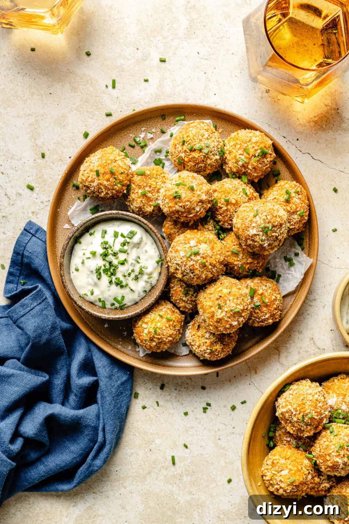 A finished plate of Crispy Crab Cake Bites on a cream countertop with a side of the tarragon aoili.