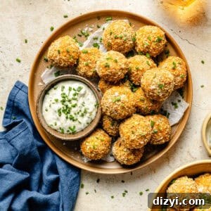 A finished plate of Crispy Crab Cake Bites on a cream countertop with a side of the tarragon aoili.