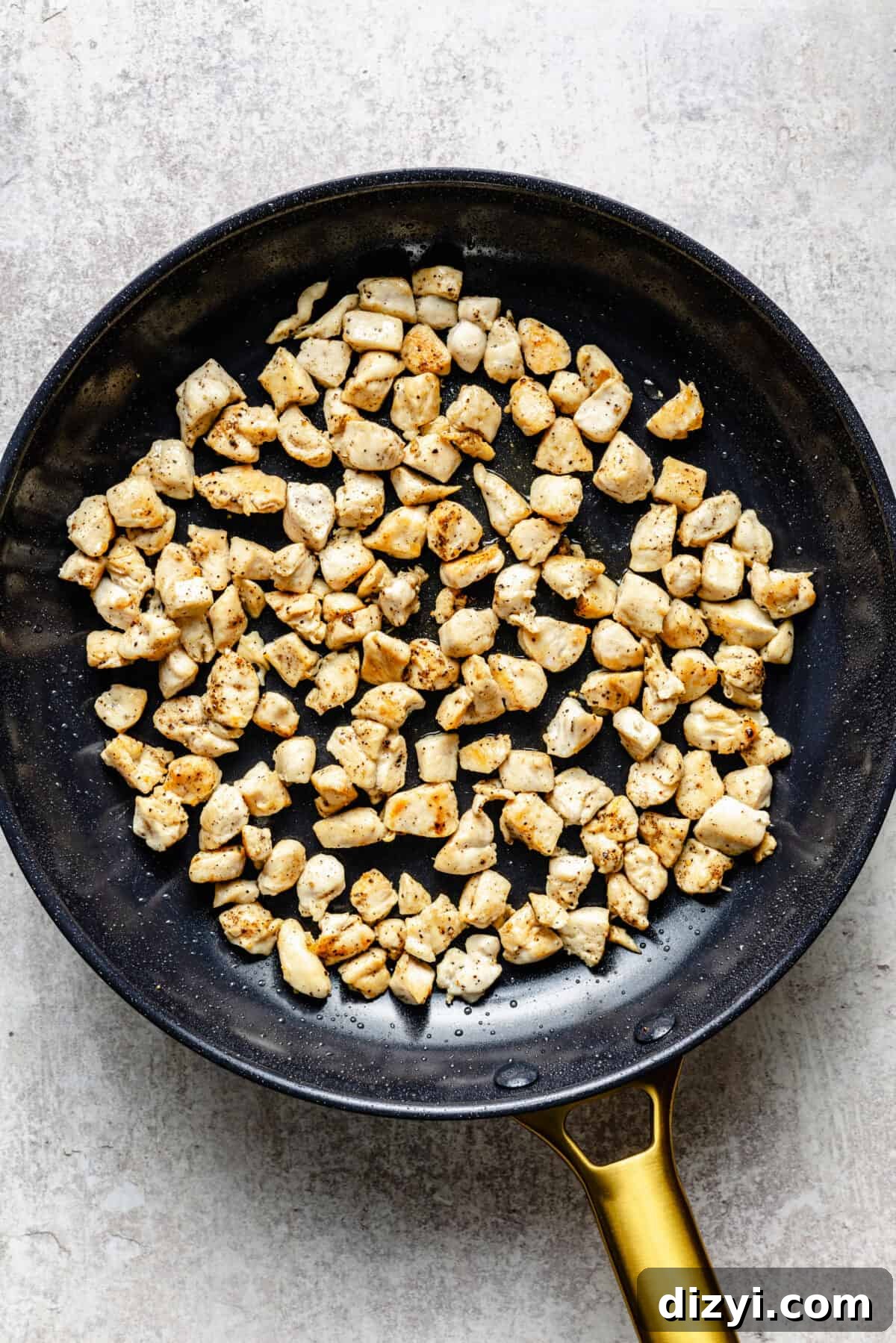 The chicken for Simple Chicken Fried Rice browning in a black skillet with a gold handle.
