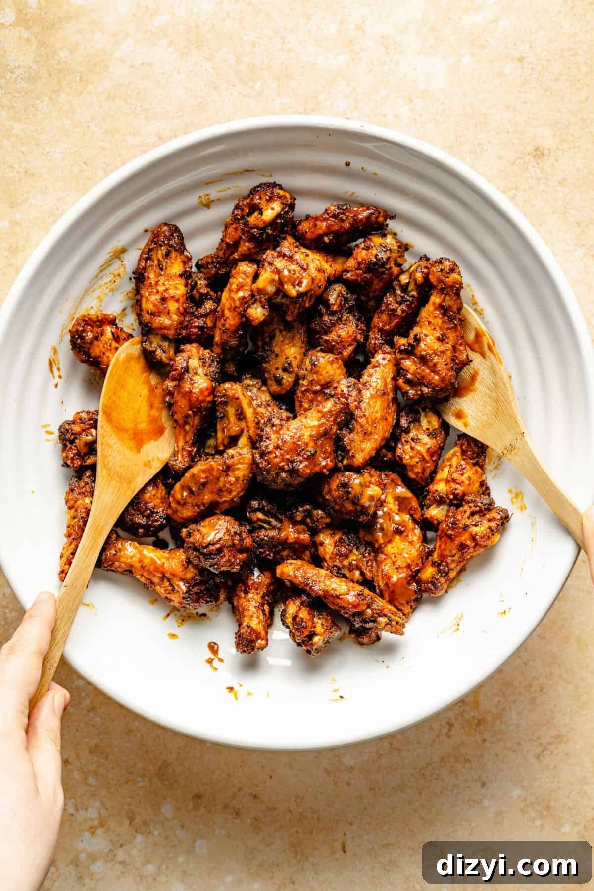 Cajun Spiced Chicken Wings in a bowl being tossed in sauce.