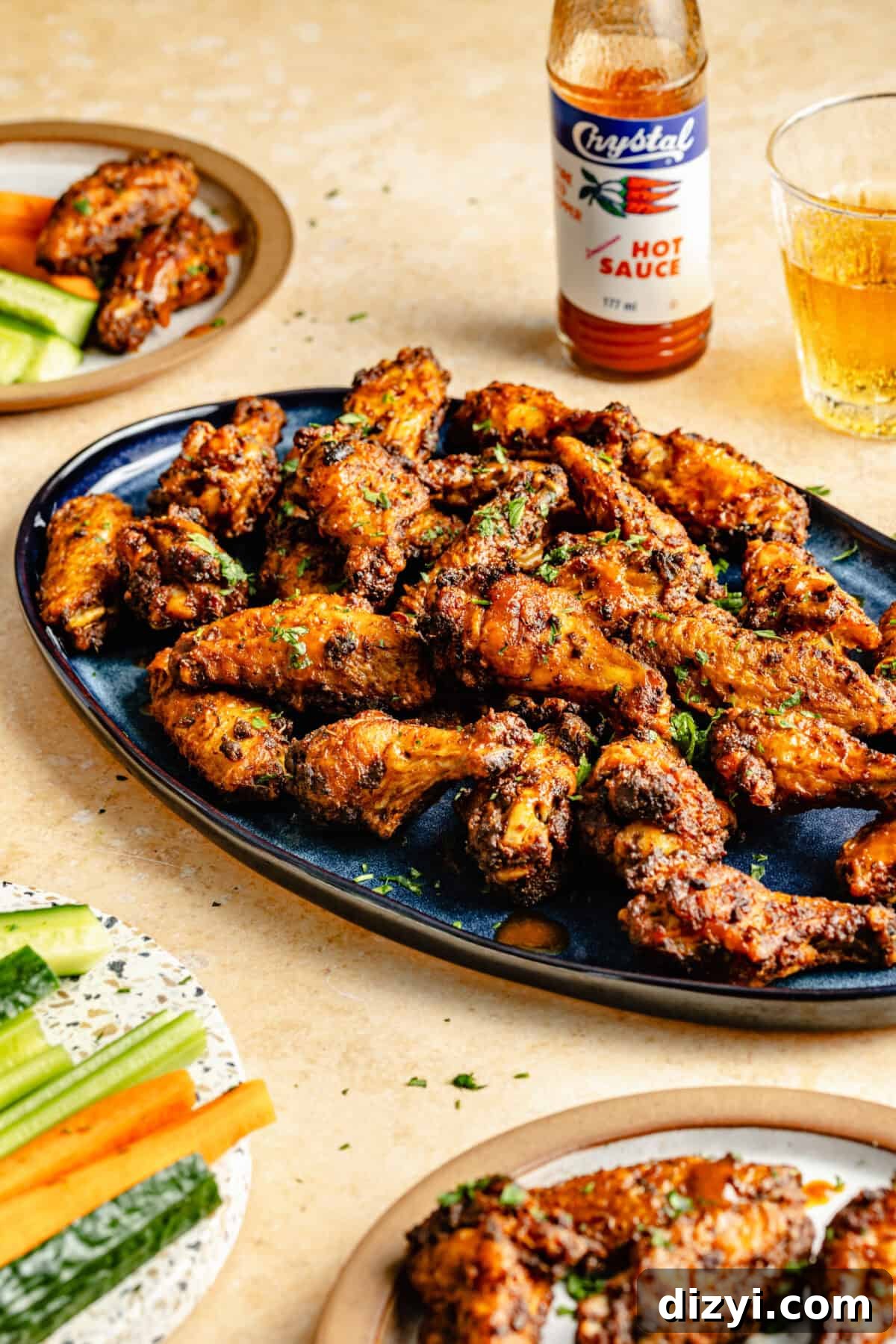 Cajun Spiced Chicken Wings on blue oval platter. Beer and cute veggies on the side.