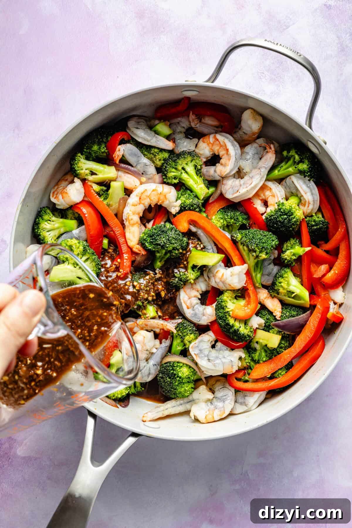 Shrimp and veggie stir fry in pan with sauce pouring in