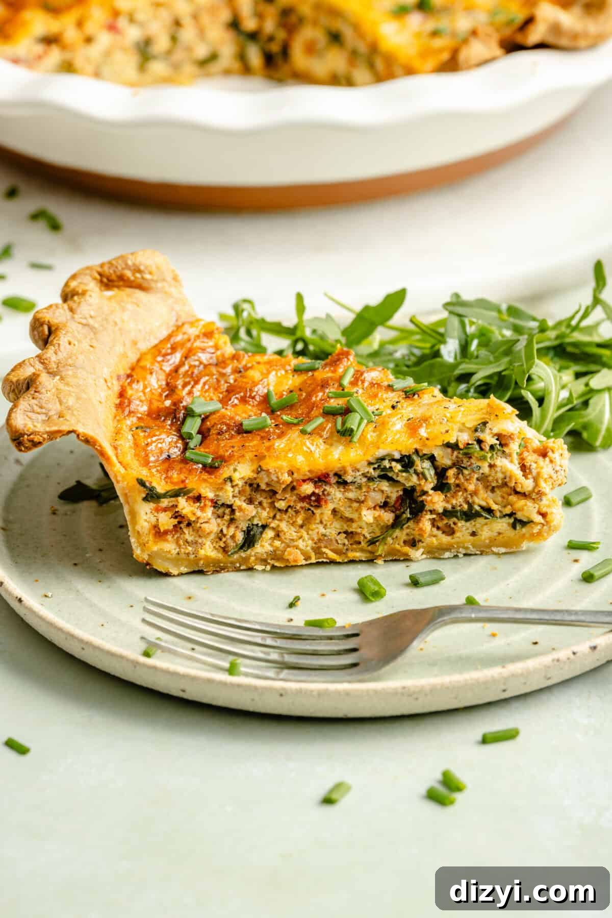 Slice of Italian Sausage and Arugula Quiche on plate.
