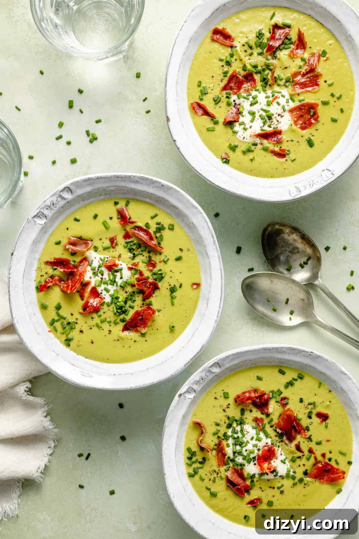 Cream of Asparagus Soup with Crispy Prosciutto in three serving bowls.