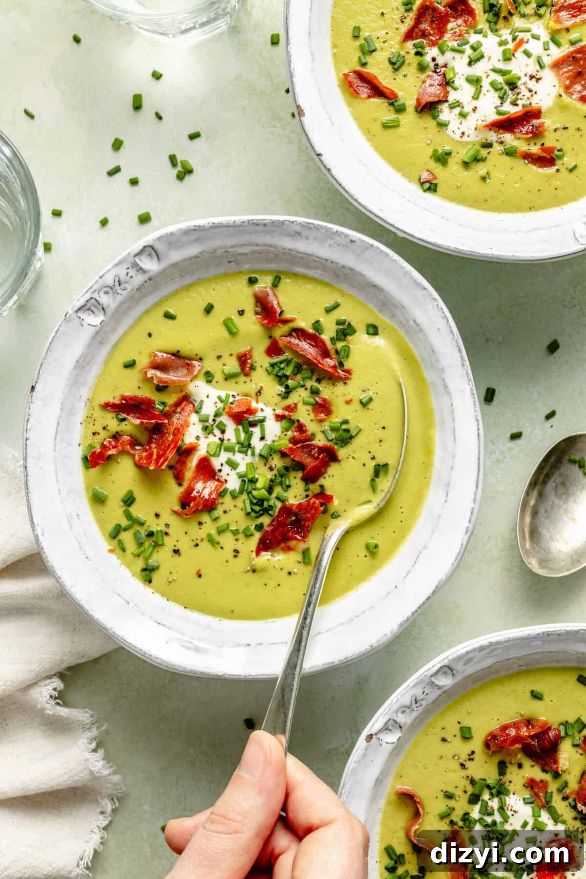 Cream of Asparagus Soup with Crispy Prosciutto in bowl with spoon.