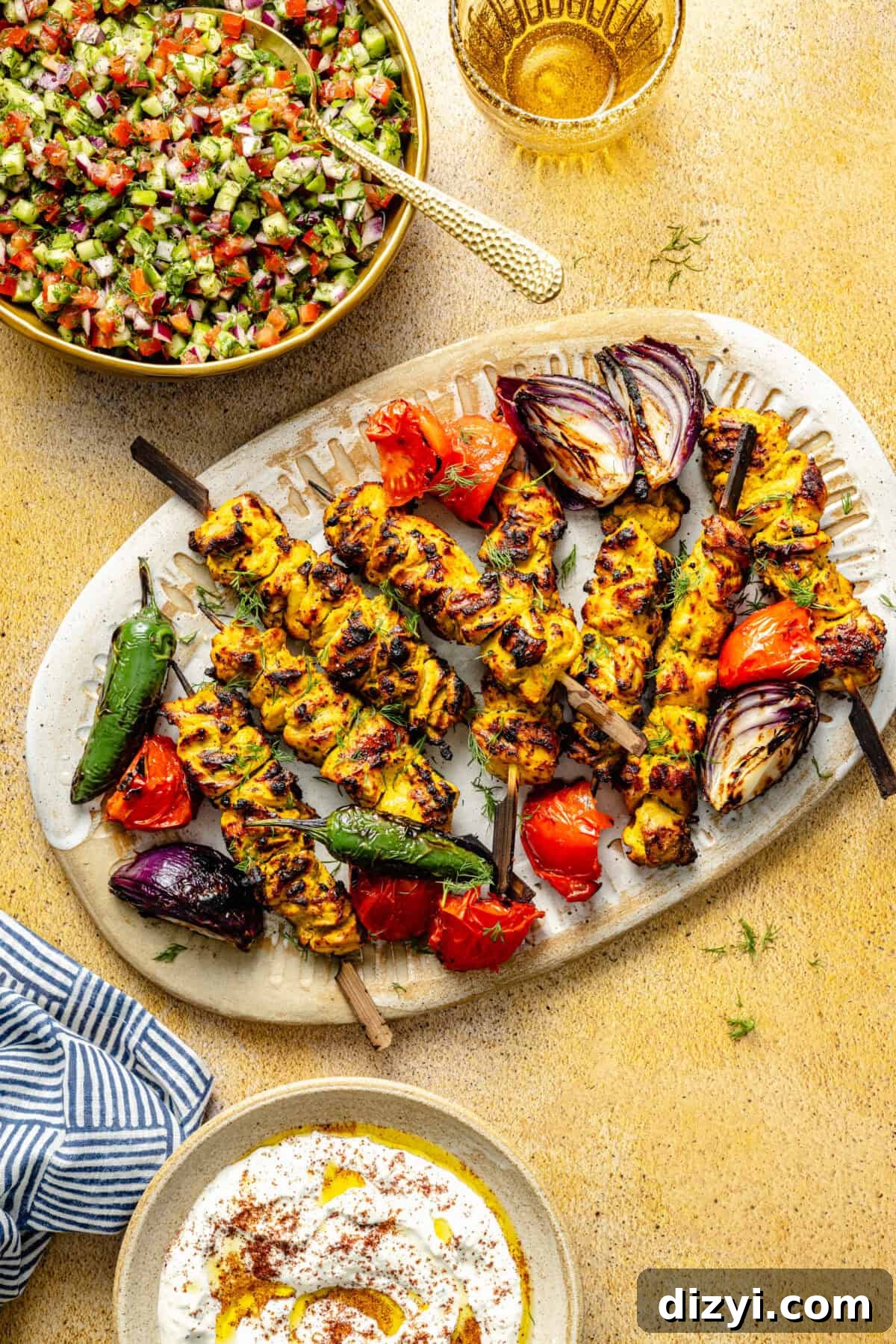 Persian-Inspired Chicken Kebabs on platter with salad and sauce in bowls surrounding.