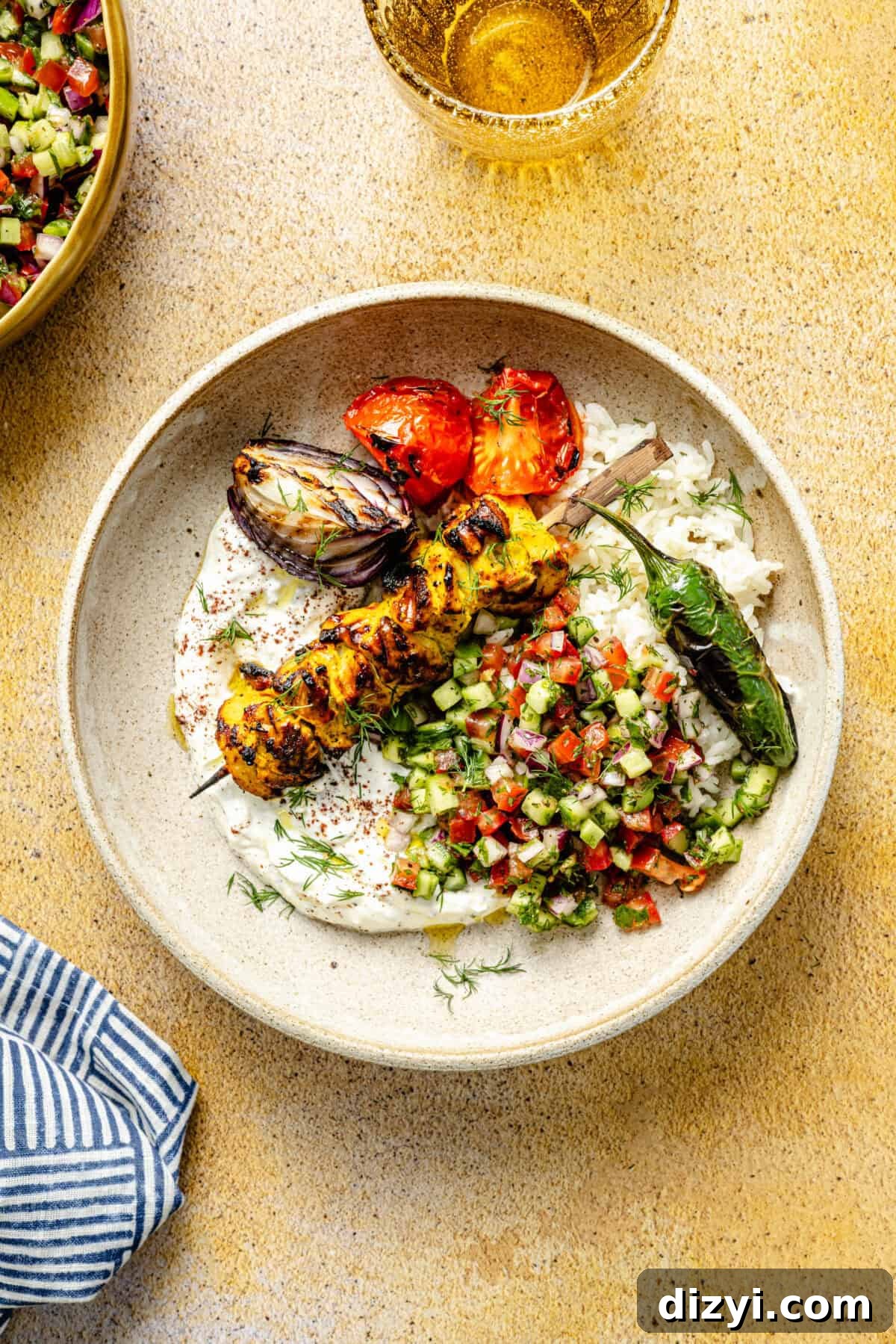 Persian-Inspired Chicken Kebabs plated with veggies, rice, salad, and sauce in bowl.