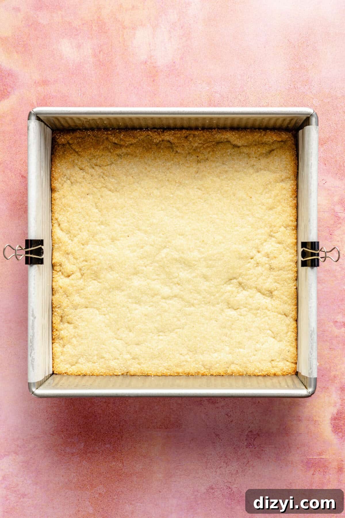 a square baking tray with an almond flour crust on a pink background