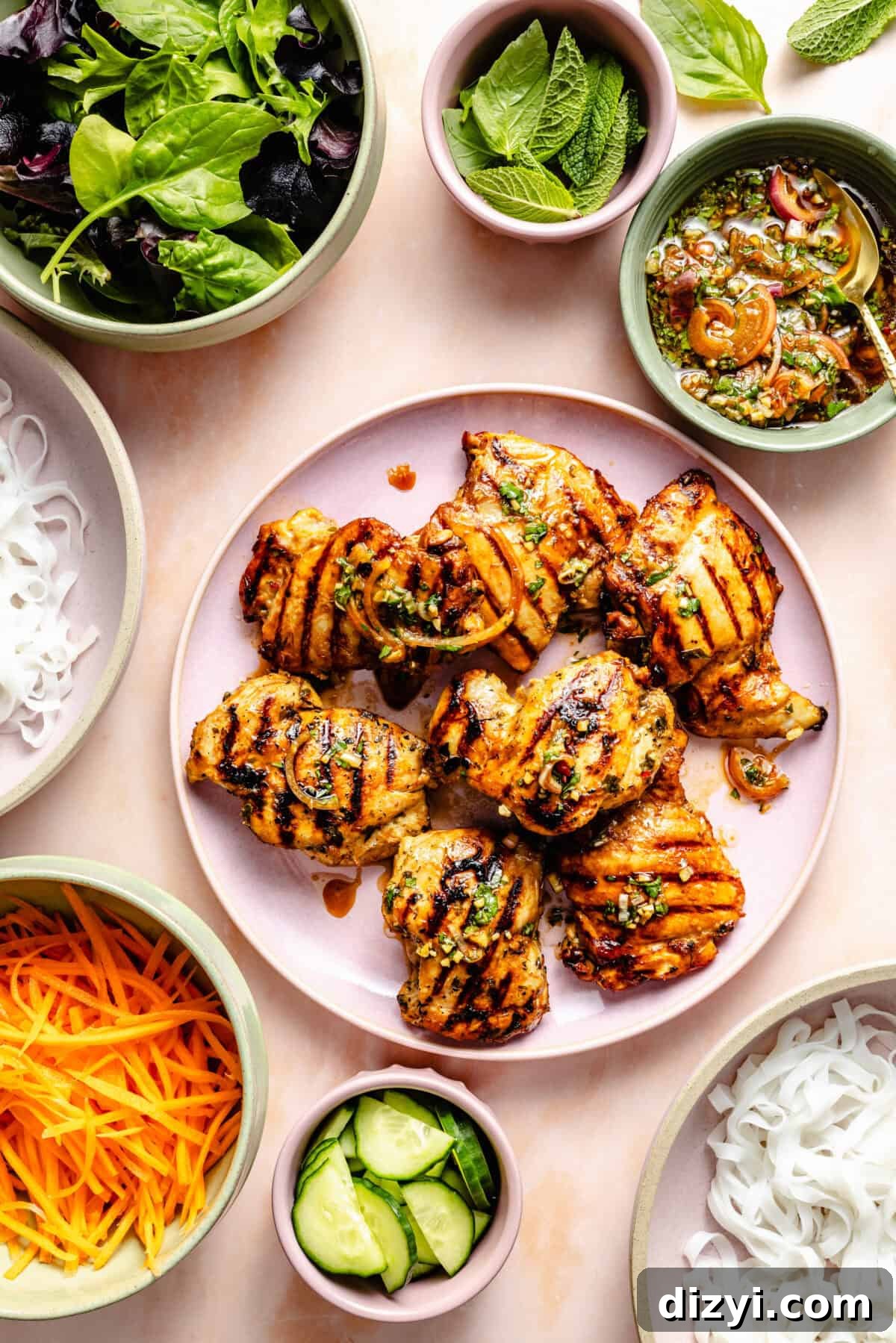 Vietnamese Chicken Noodle Bowls with Lime and Fresh Herbs 4 grilled boneless, skinless chicken thighs on a light pink platter with fresh vegetables and rice noodles