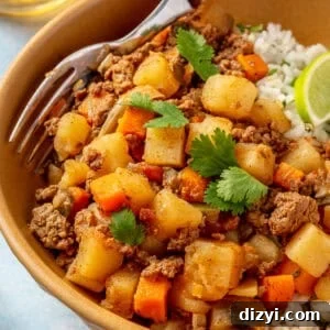 A close up shot of the finished Crockpot Mexican Picadillo in an orange bowl served with rice and garnished with lime and cilantro.