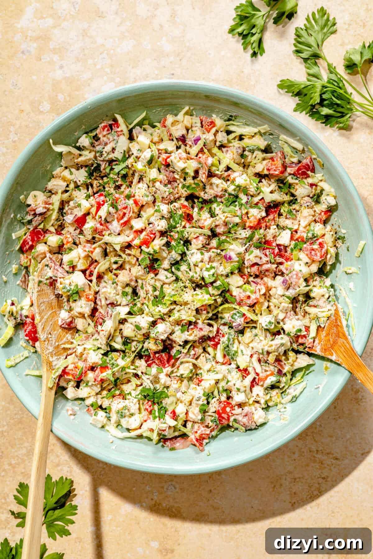 Deli-Style Chopped Chicken Salad Recipe 4 a green bowl of prepared chopped chicken salad with two wooden spoons