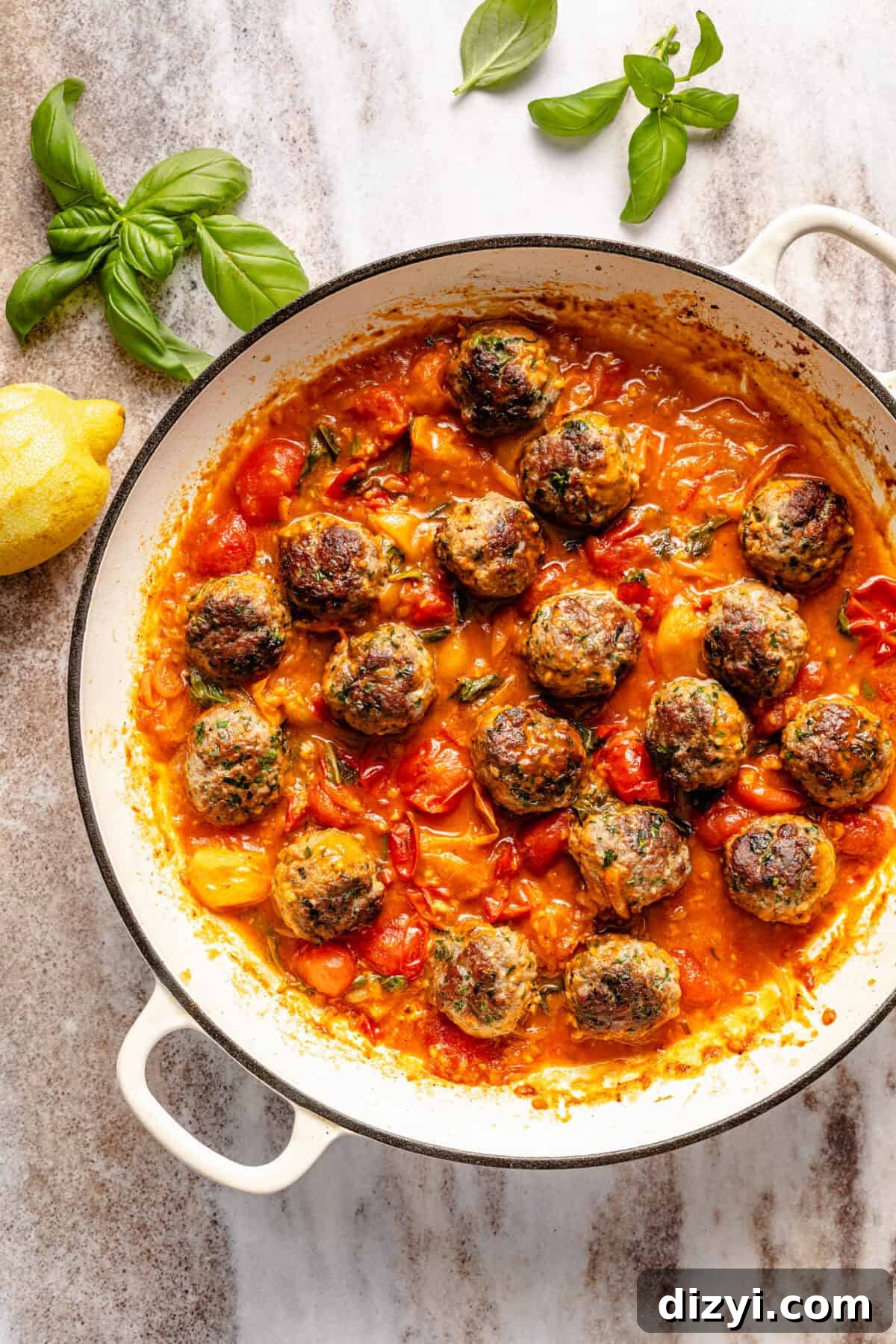 cooked meatballs simmer in a burst tomato sauce with fresh basil and lemon