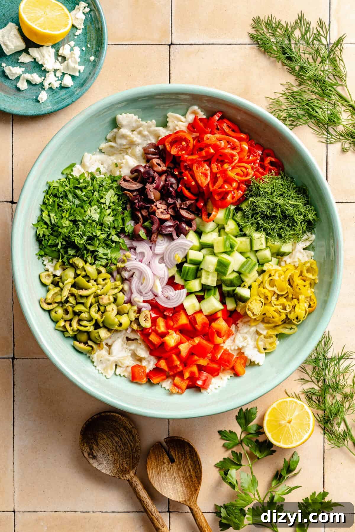 Classic Greek Pasta Salad with Feta and Kalamata Olives 4 an array of chopped vegetables including cucumbers, bell peppers, olives, shallots, and fresh herbs in a light green bowl