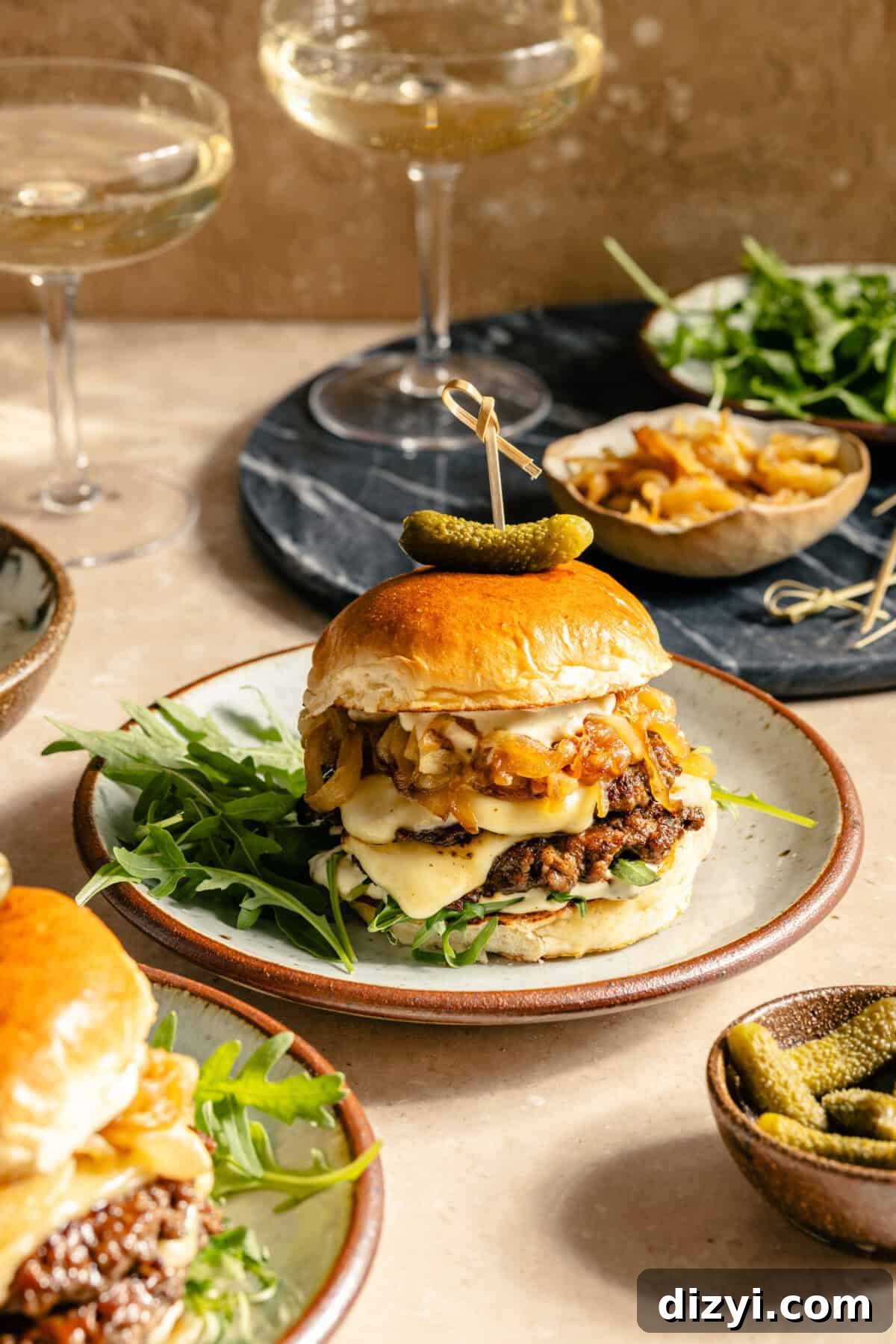a double smashburger with cheese, caramelized onions, and arugula on a white and red plate with martini glasses