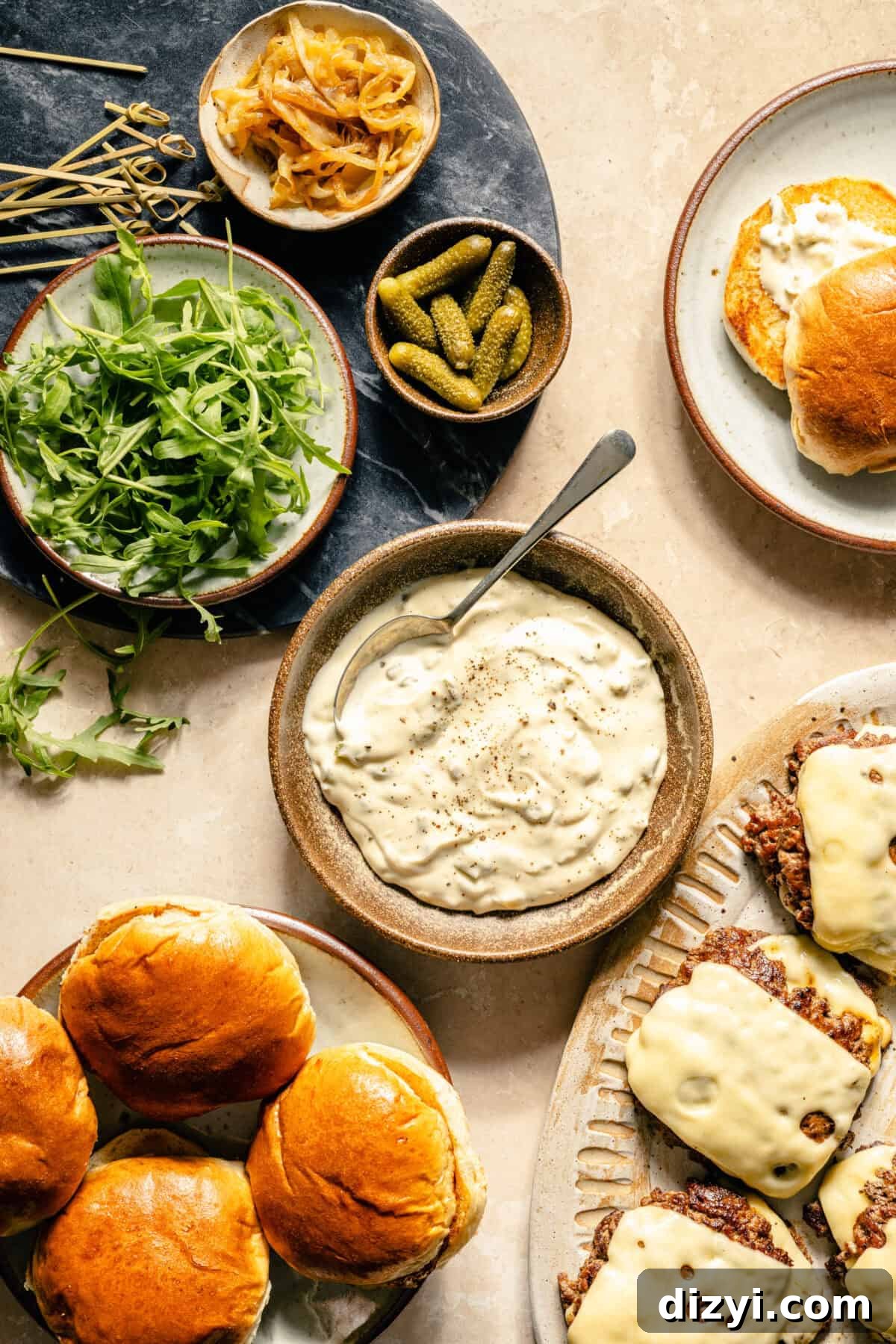 a brown bowl with truffle sauce and a side of fresh baby arugula, cornichons, and brioche burger buns
