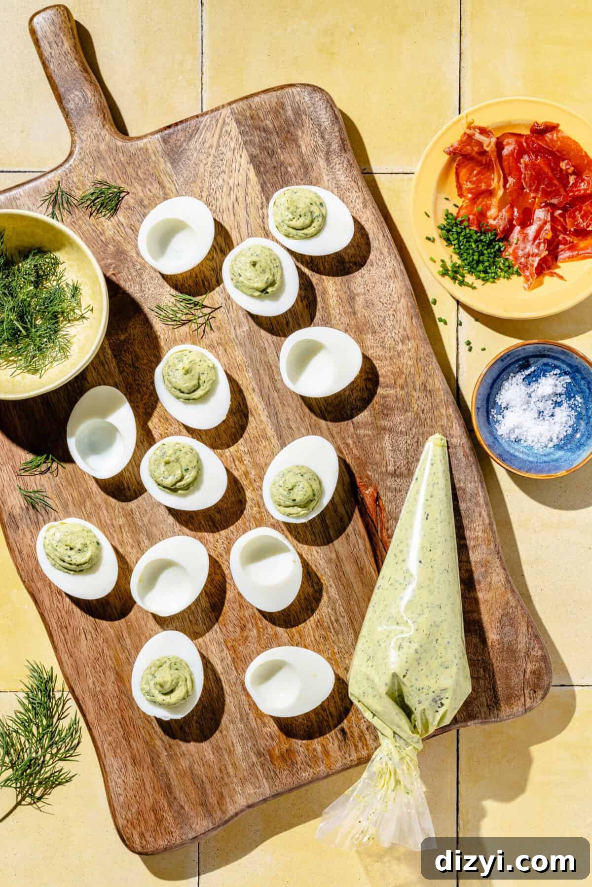 hollowed hard-boiled eggs with green goddess dressing on a wooden cutting board and yellow background