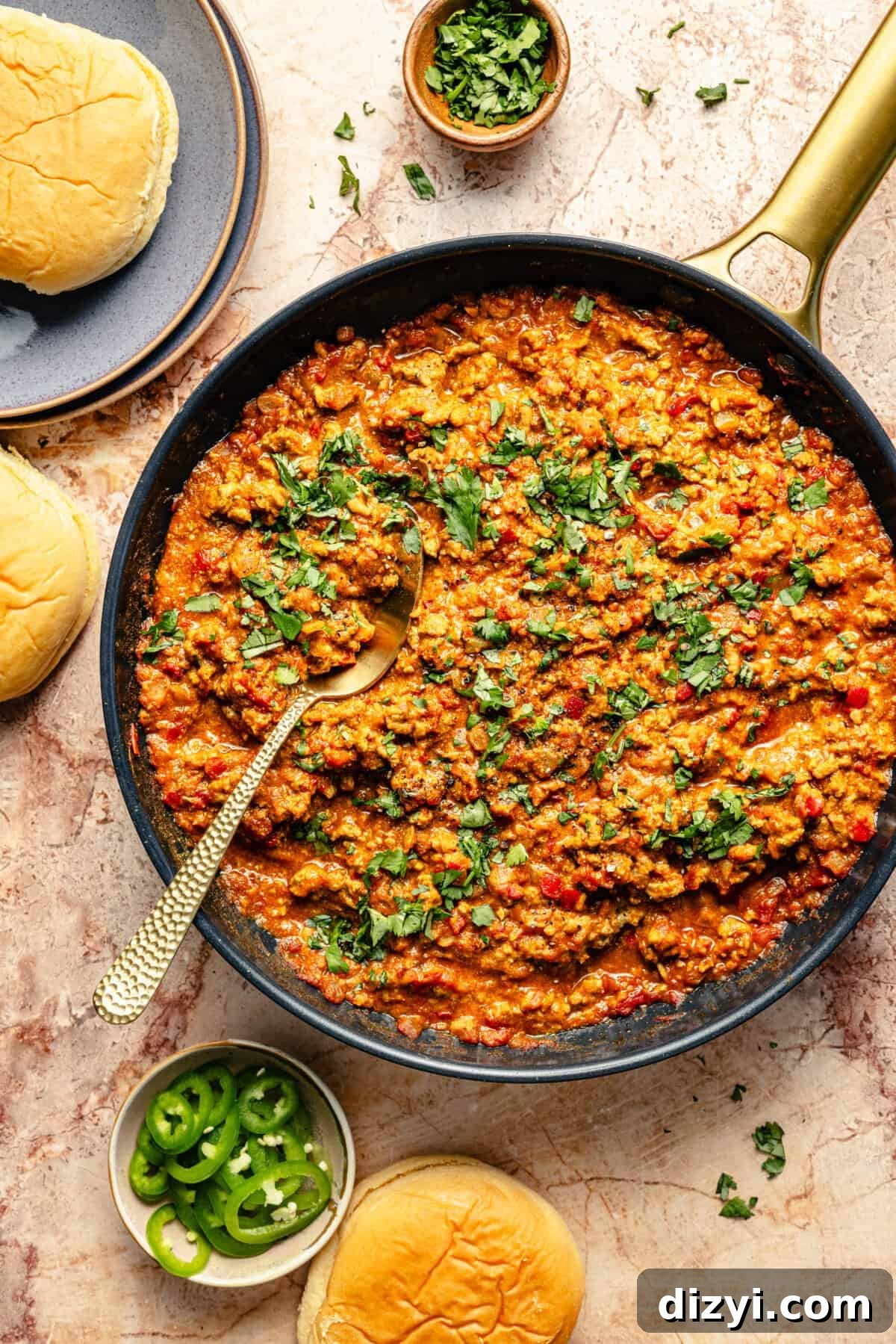 a large skillet with curried turkey sloppy joes topped with chopped cilantro and served with potato buns