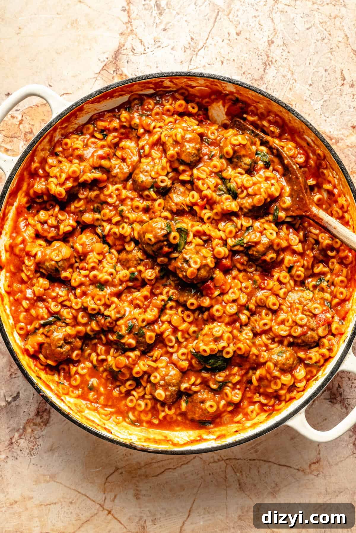 a cast-iron braiser with cooked pasta, mini meatballs, and marinara sauce