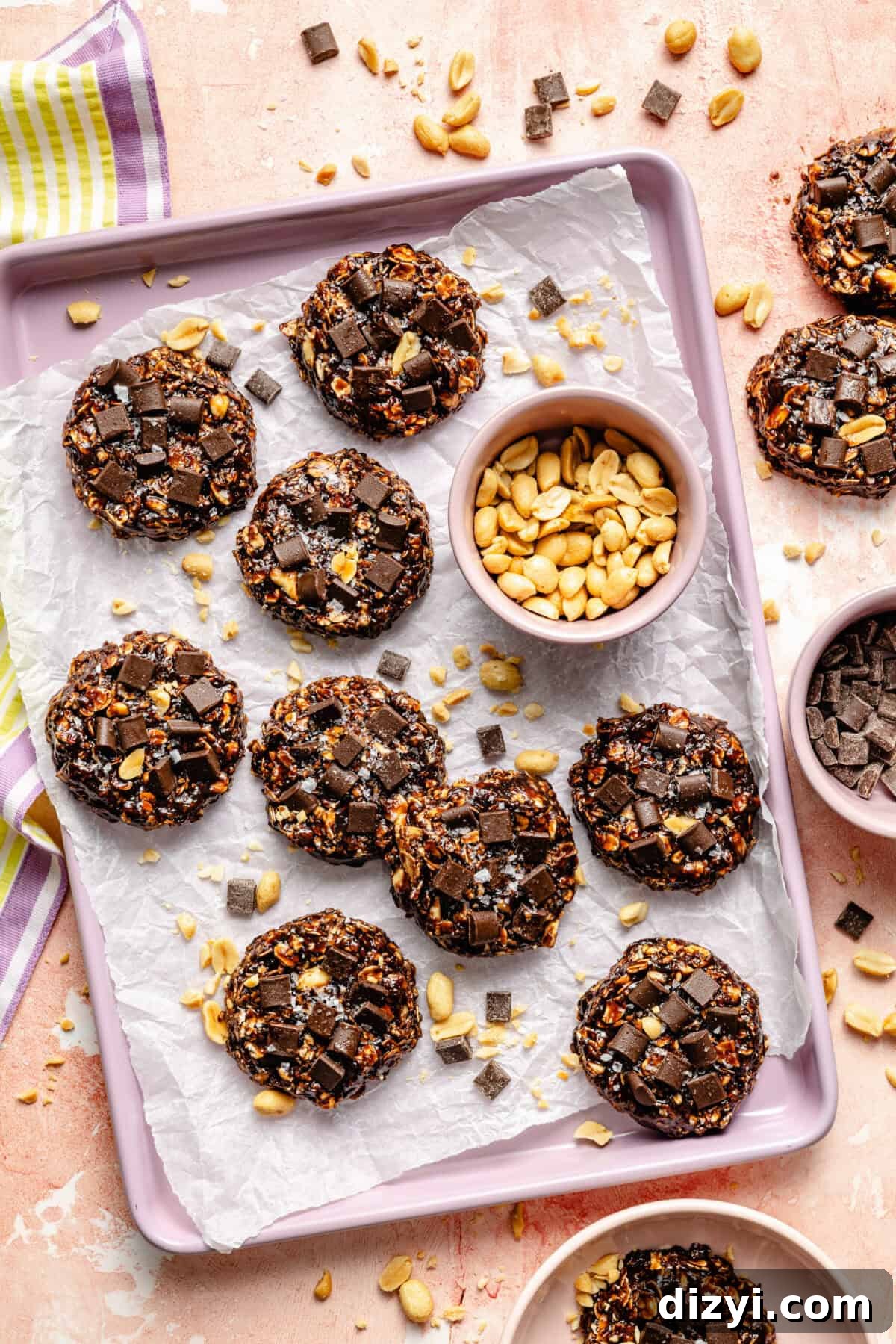 No-Bake Chocolate Peanut Butter Cookies Recipe 2 a tray of no-bake chocolate oat cookies and salted peanuts on a light pink background
