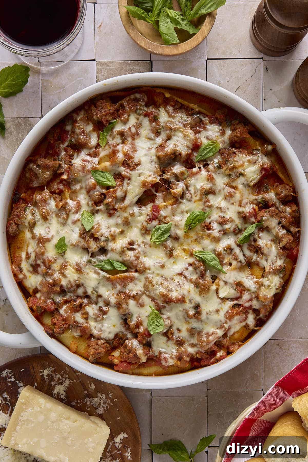 a stoneware dish with cheese stuffed shells, marinara sauce, melted mozzarella cheese, and basil