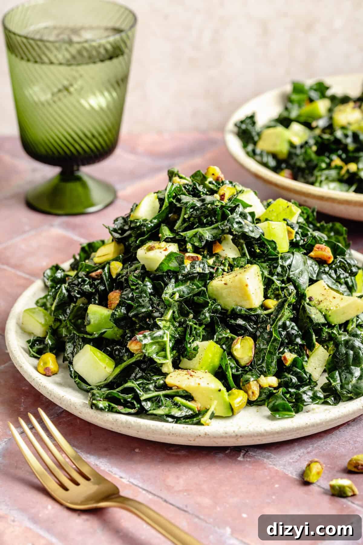 Citrus Kale Detox Salad with Lemon Ginger Dressing 4 a plate with a mound of shredded kale salad including avocado, green apples, and pistachios with a green goblet