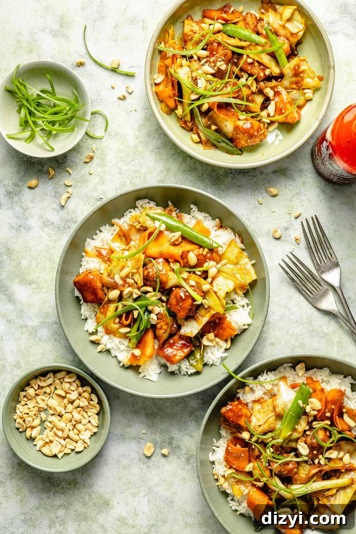 plated spicy Sriracha chicken over white rice and garnished with chopped peanuts and green onions