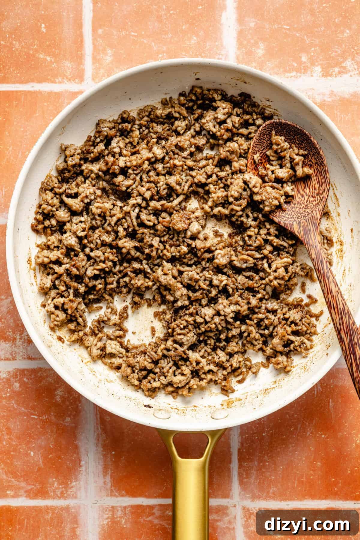 One-Pan Mediterranean Beef and Vegetable Skillet Recipe 3 a white and gold skillet with cooked ground beef and a wooden spoon