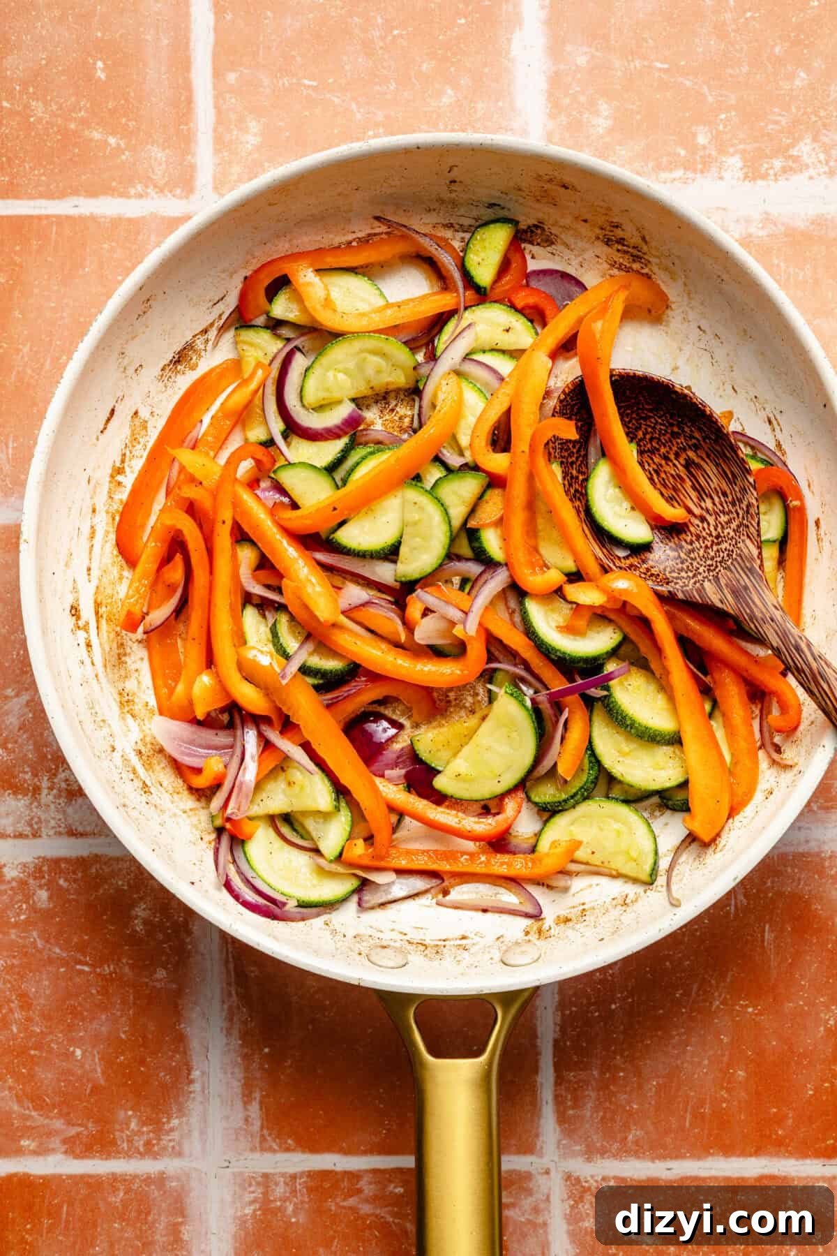 One-Pan Mediterranean Beef and Vegetable Skillet Recipe 4 a white and gold skillet with zucchini, red bell peppers, and red onions on a red tile background