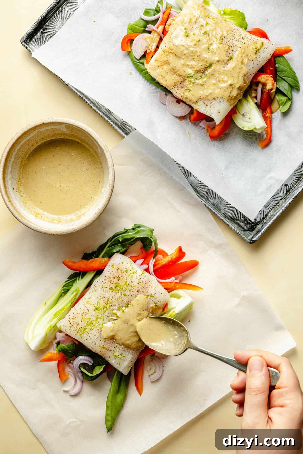 two sheets of parchment paper with fish, vegetables, and green curry sauce