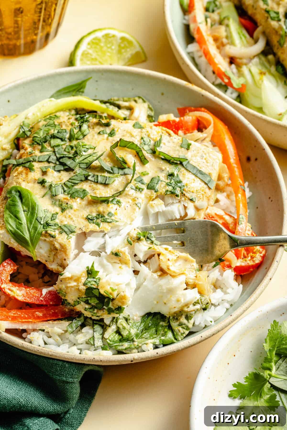 an up-close shot of green curry fish with vegetables, white rice, and herbs