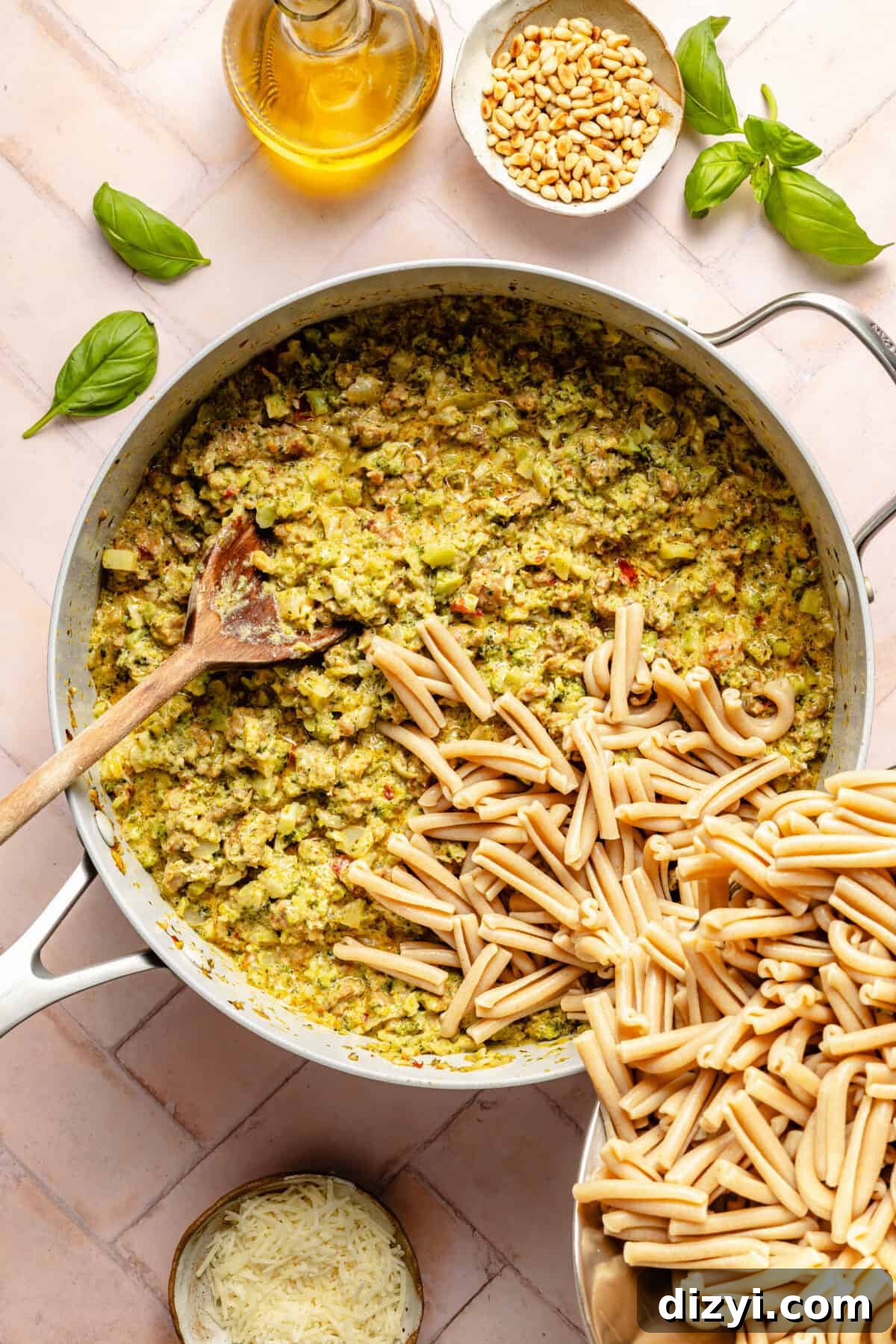 Creamy Pesto Pasta with Sausage and Broccoli 3 a large pot with prepared broccoli-pesto sauce and cooked pasta with a jug of olive oil and a side of pine nuts
