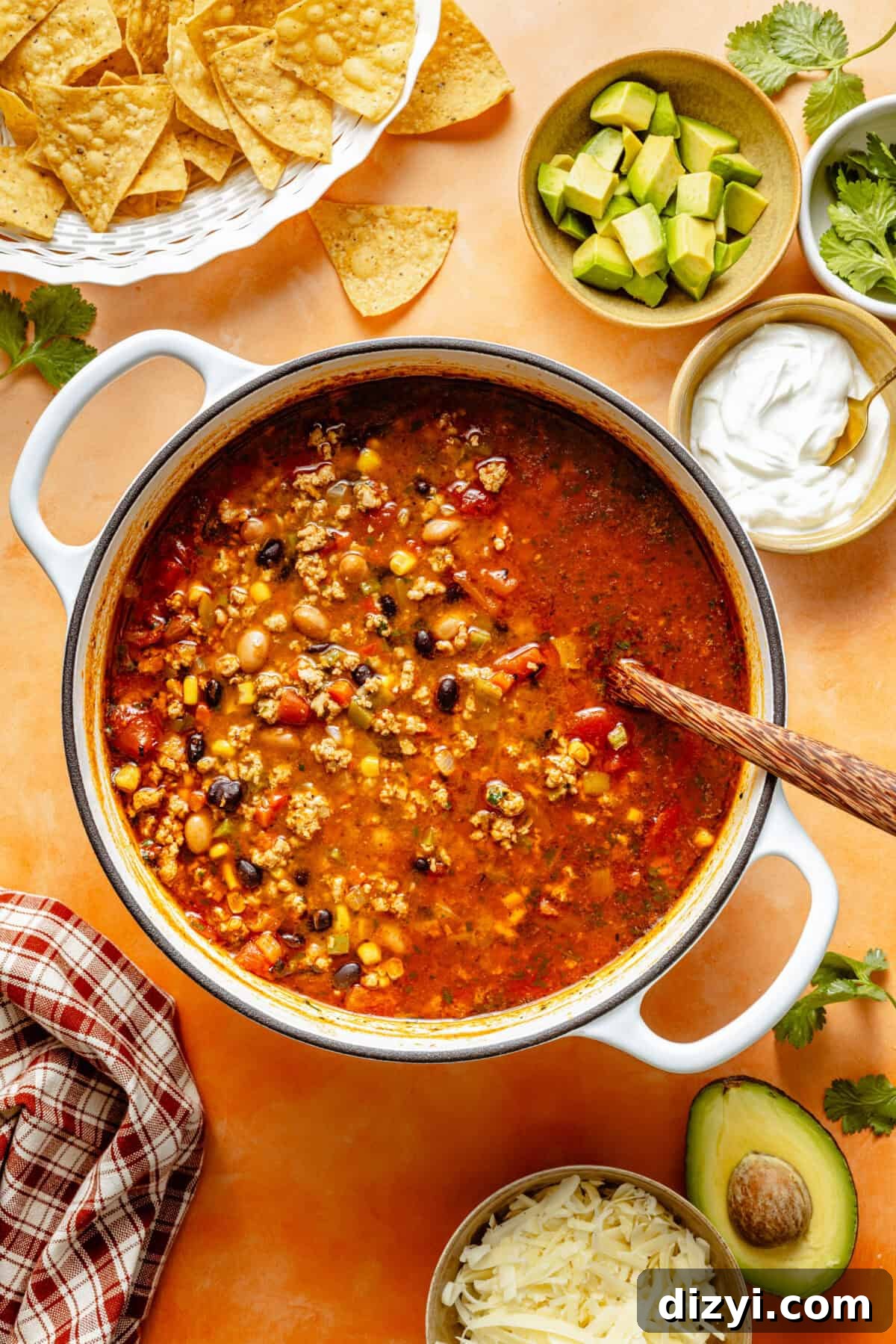 Turkey Taco Soup with Black Beans and Corn 4 a large pot of turkey taco soup with a side of cubed avocado, sour cream, shredded cheese, and tortilla chips