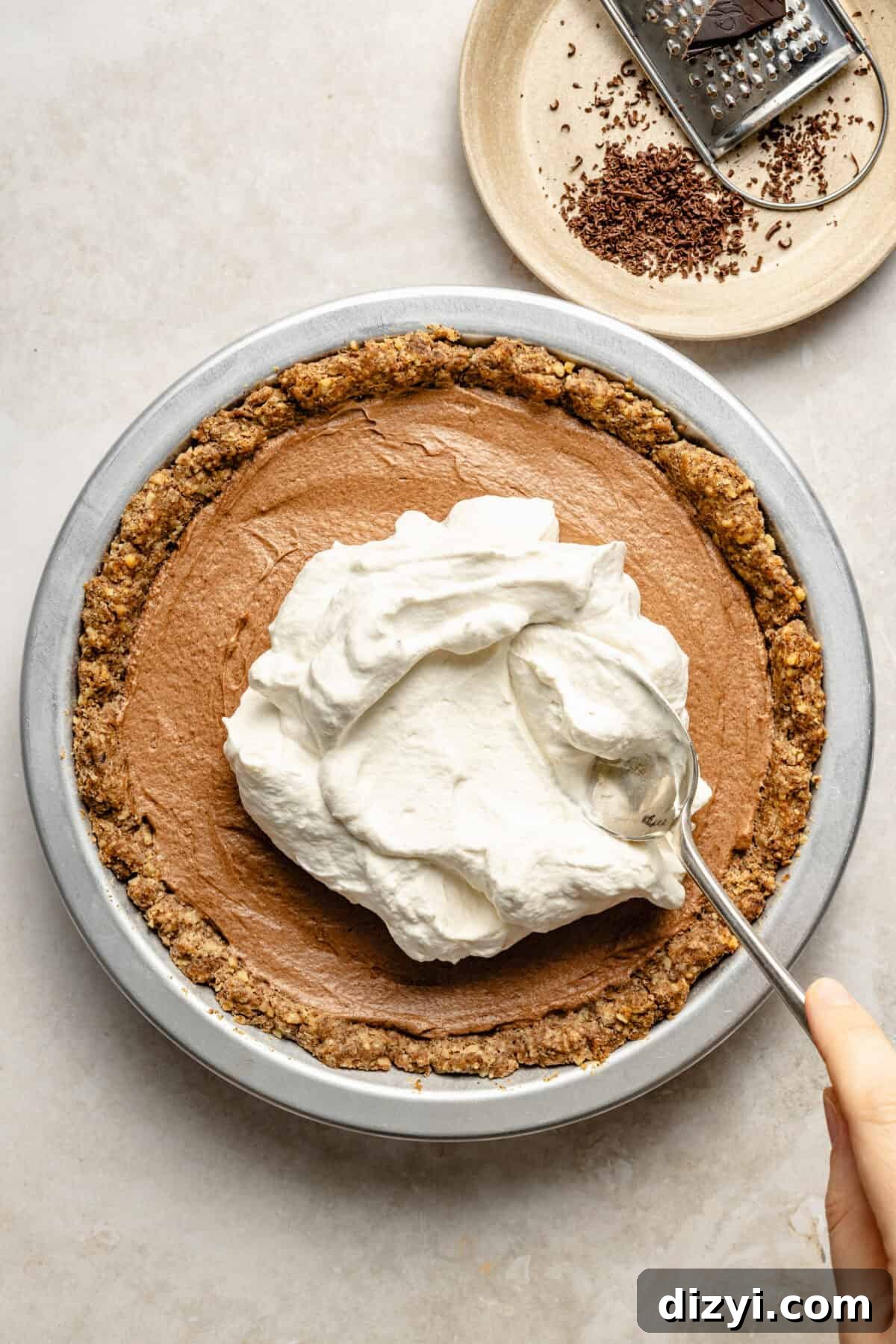 a metal baking dish with a whipped chocolate filling and whipped cream topping on a neutral background