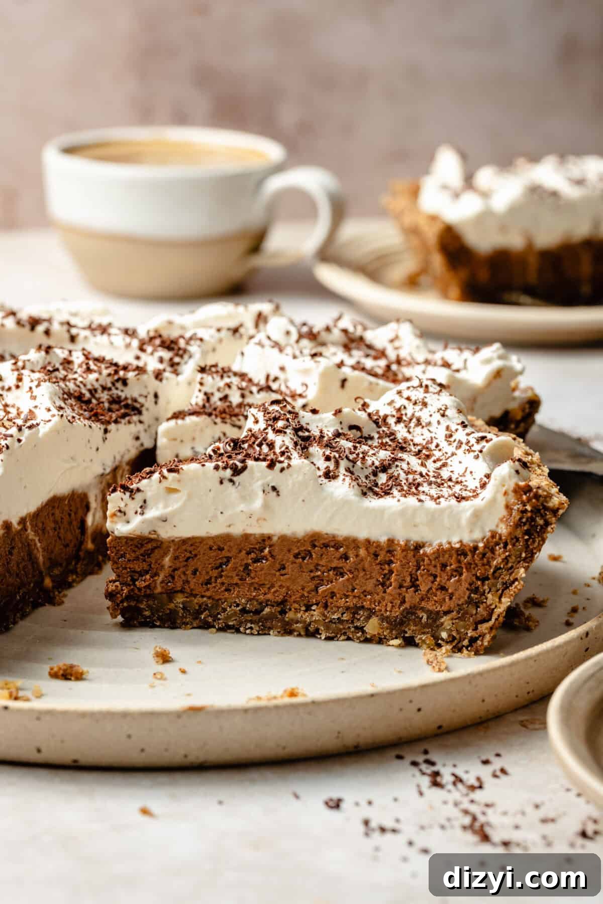 an up-close photo of a chocolate, coffee, and walnuts pie with a whipped cream topping and chocolate shavings on a neutral background