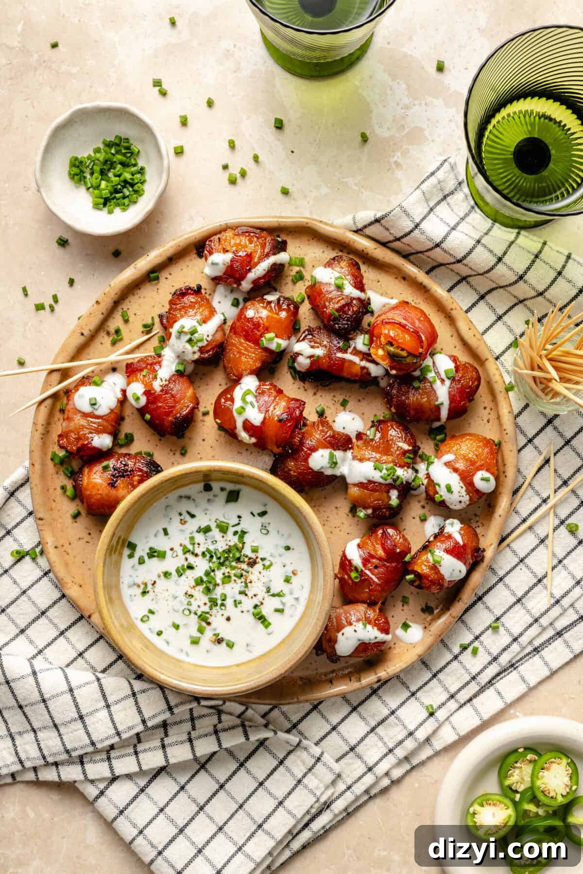 Bacon Wrapped Apricot Bites with Blue Cheese Drizzle 2 a plate of crispy bacon-wrapped apricots stuffed with jalapeno peppers and topped with a blue cheese dressing and fresh chives
