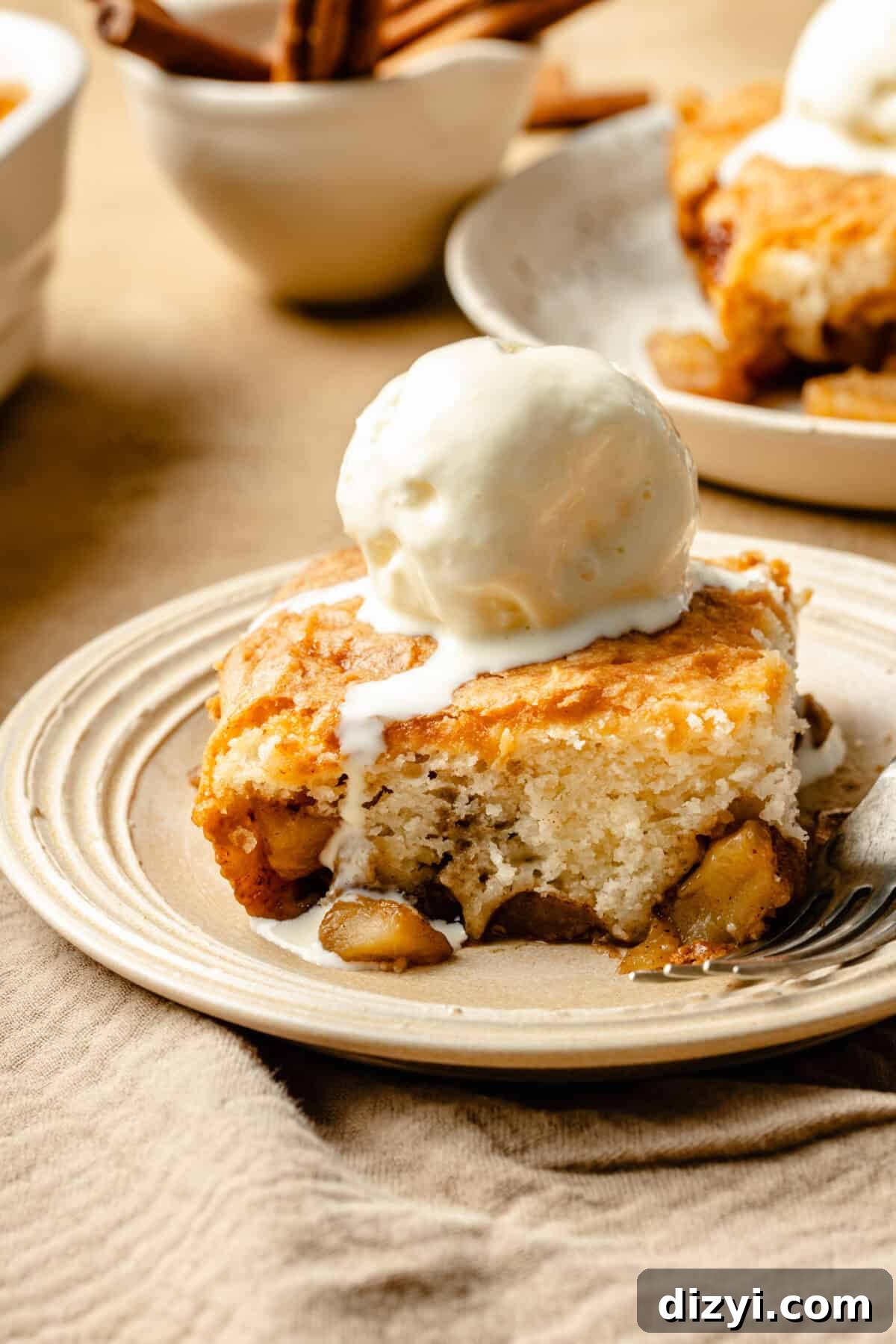 a slice of apple dump cake on a neutral plate with a scoop of vanilla ice cream
