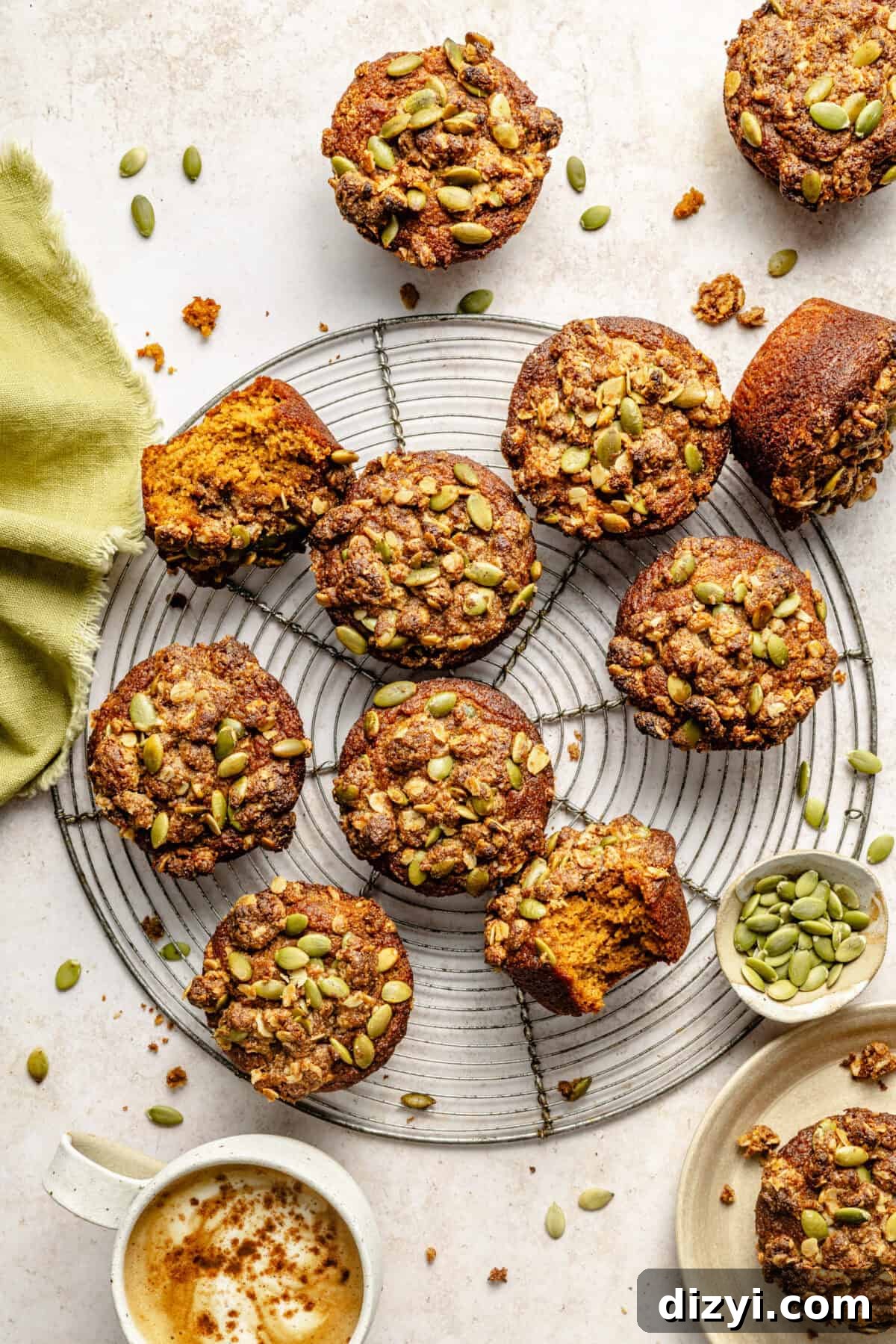 pumpkin muffins topped with pepitas streusel on a wire rack and neutral background