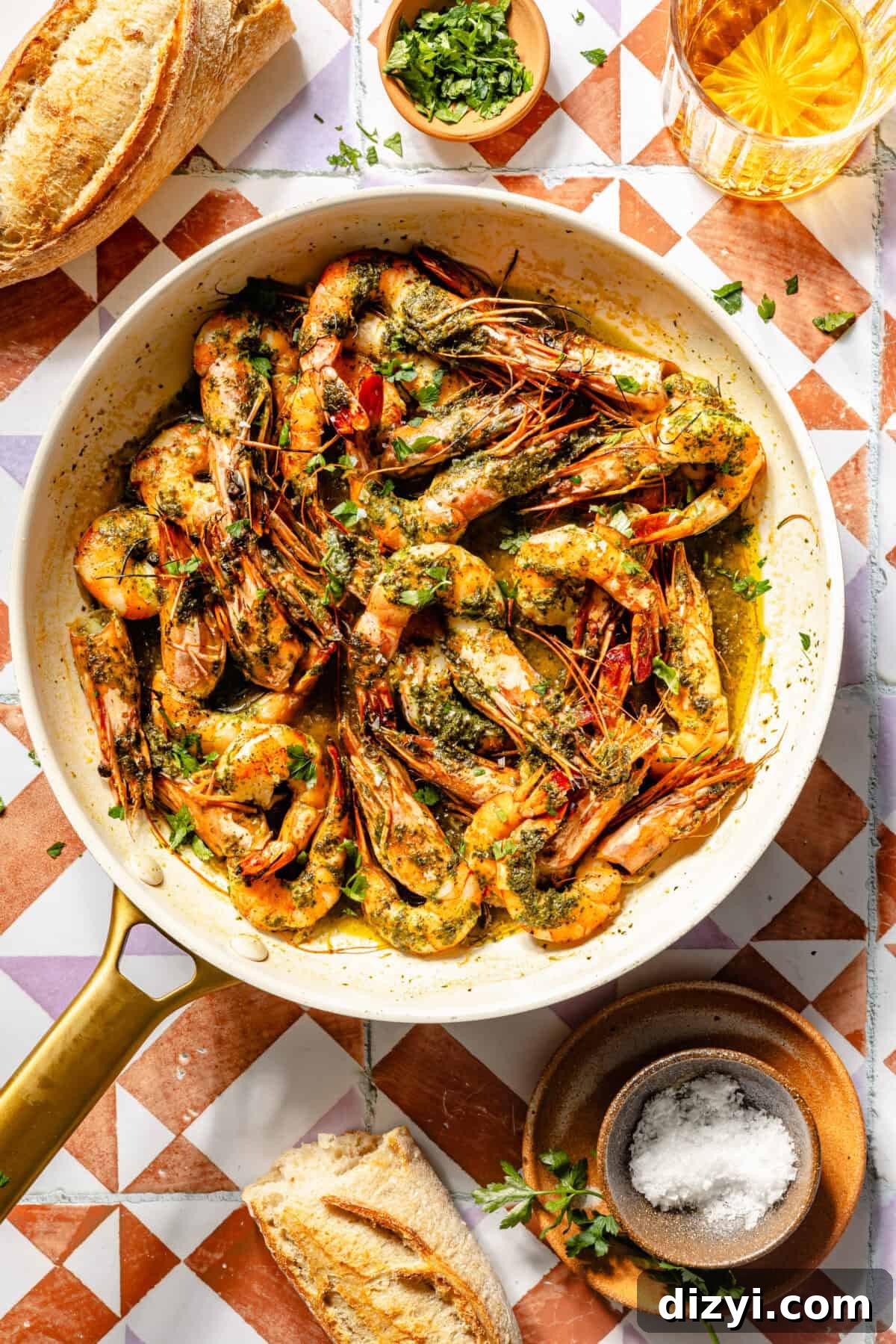 a white skillet with seared shrimp, fresh herbs, and a side of bread