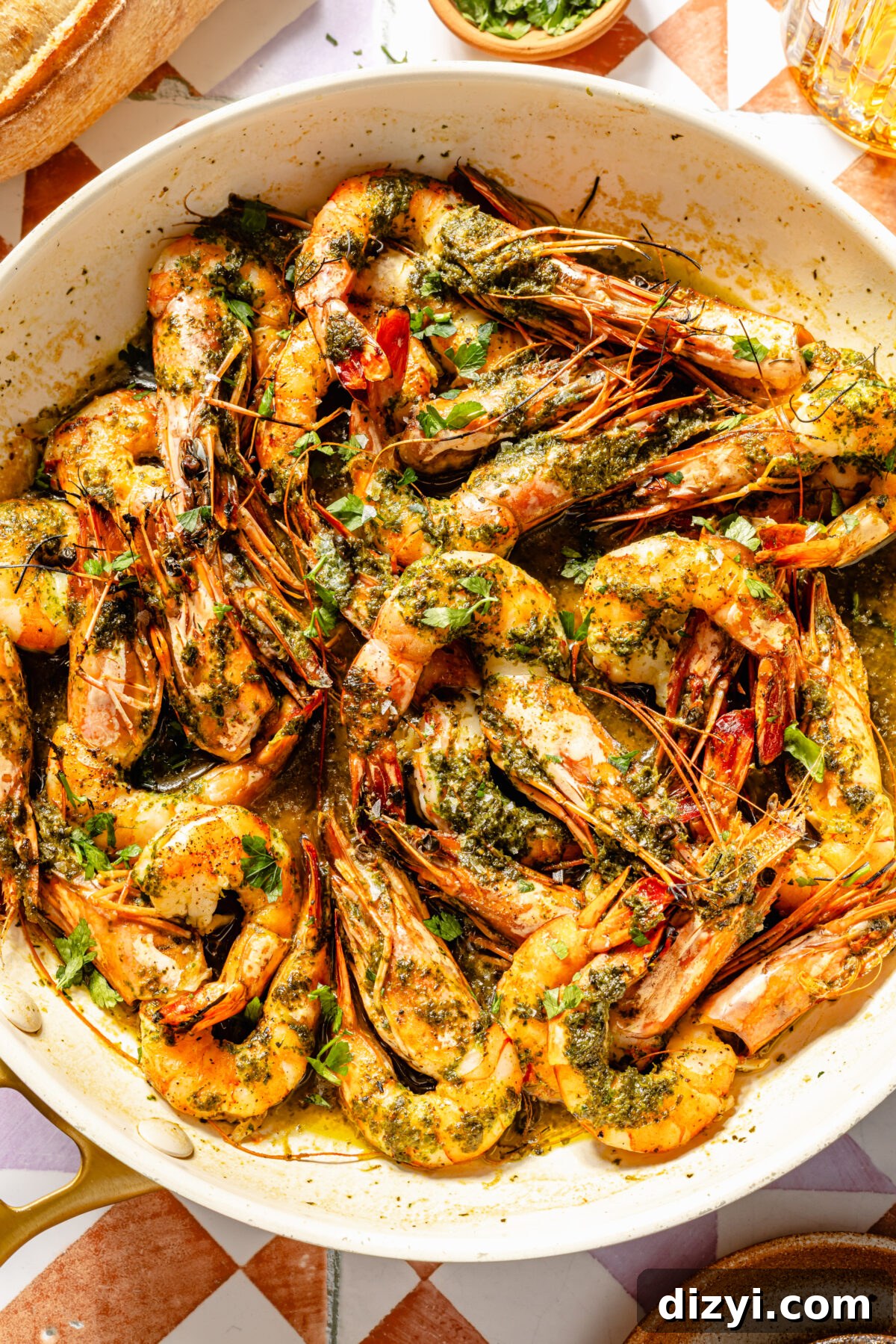 a white bowl with cooked shrimp tossed in parsley