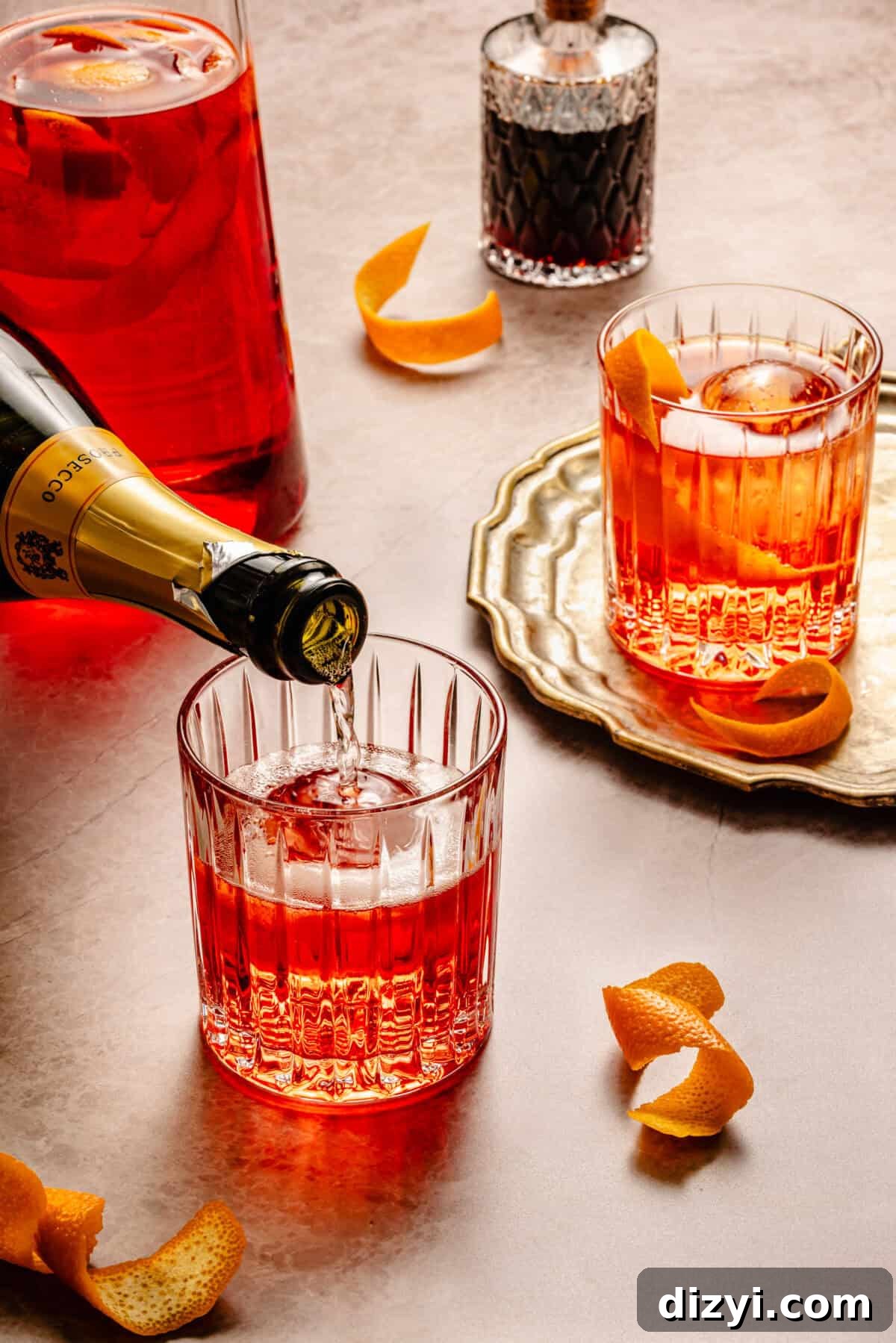 two glasses of negroni cocktails over ice with a bottle of prosecco
