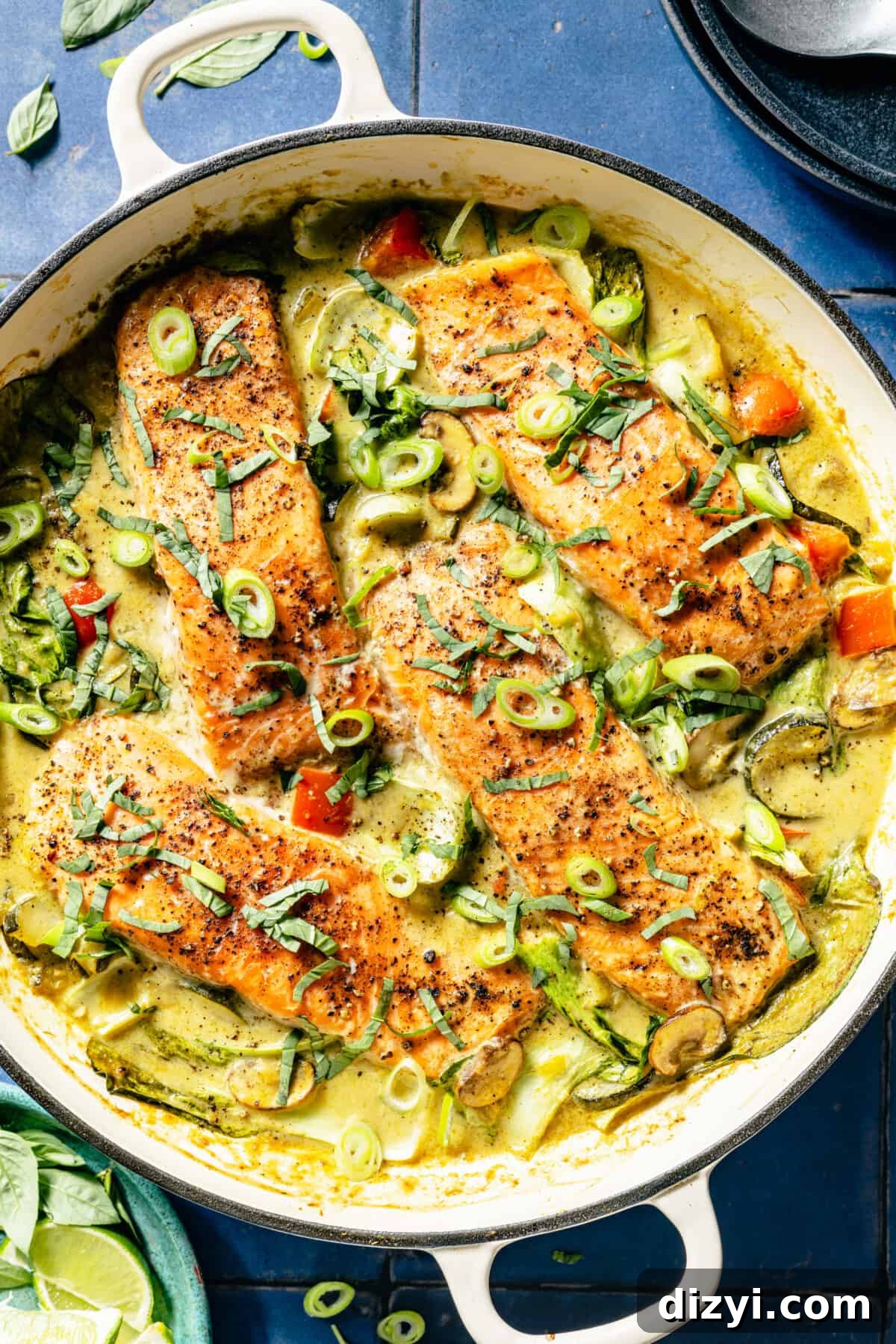 Thai Coconut Green Curry Salmon Recipe 7 Thai-Inspired Coconut Green Curry Salmon in white skillet on blue tile background.