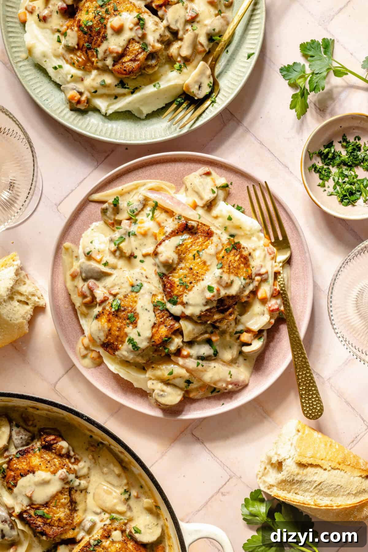two plates with seared chicken, fresh herbs, vegetables, and a creamy sauce on a light pink background