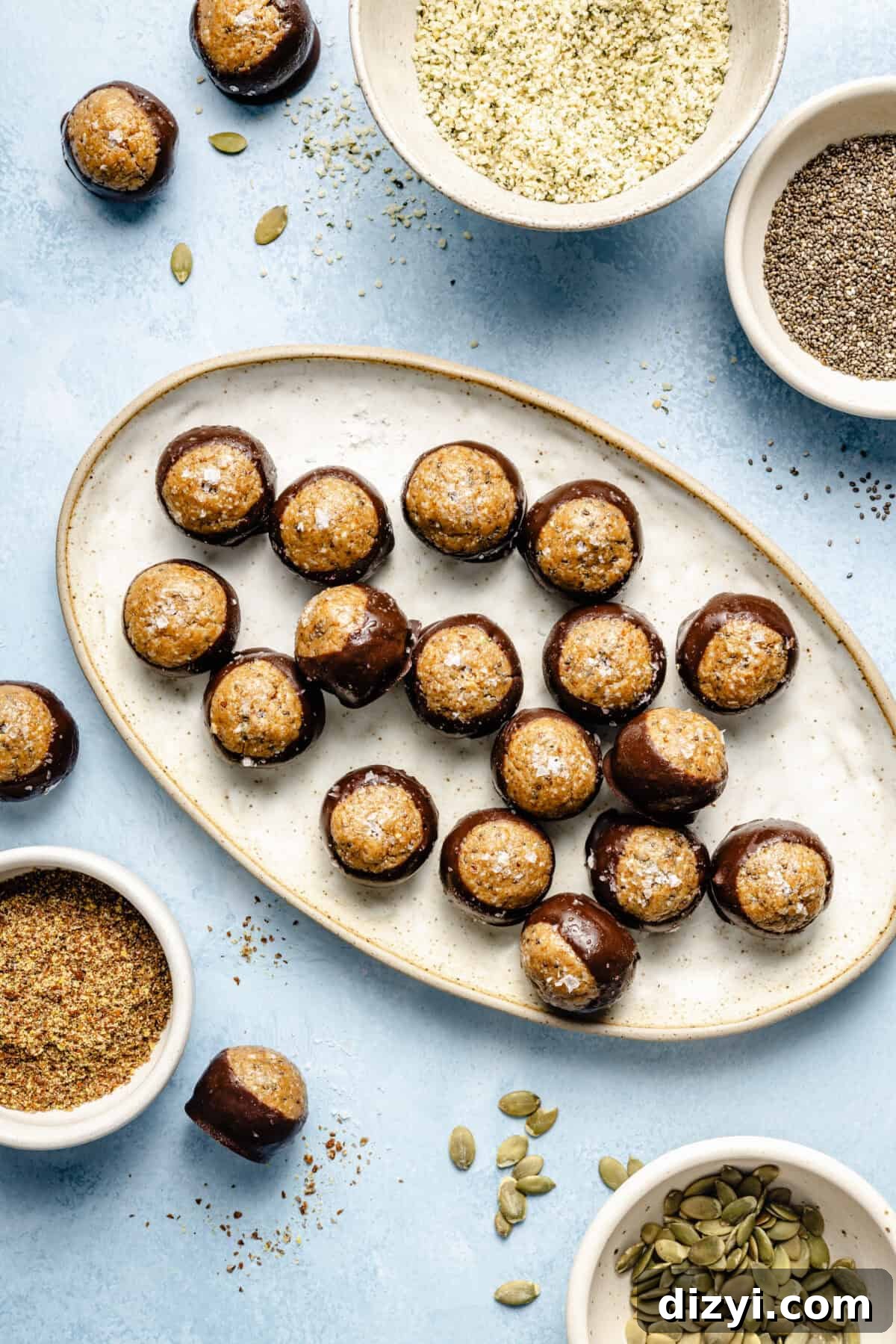 Protein-Packed, Fiber-Rich Buckeye Balls 2 a light platter on a blue background with protein balls dipped in melted chocolate