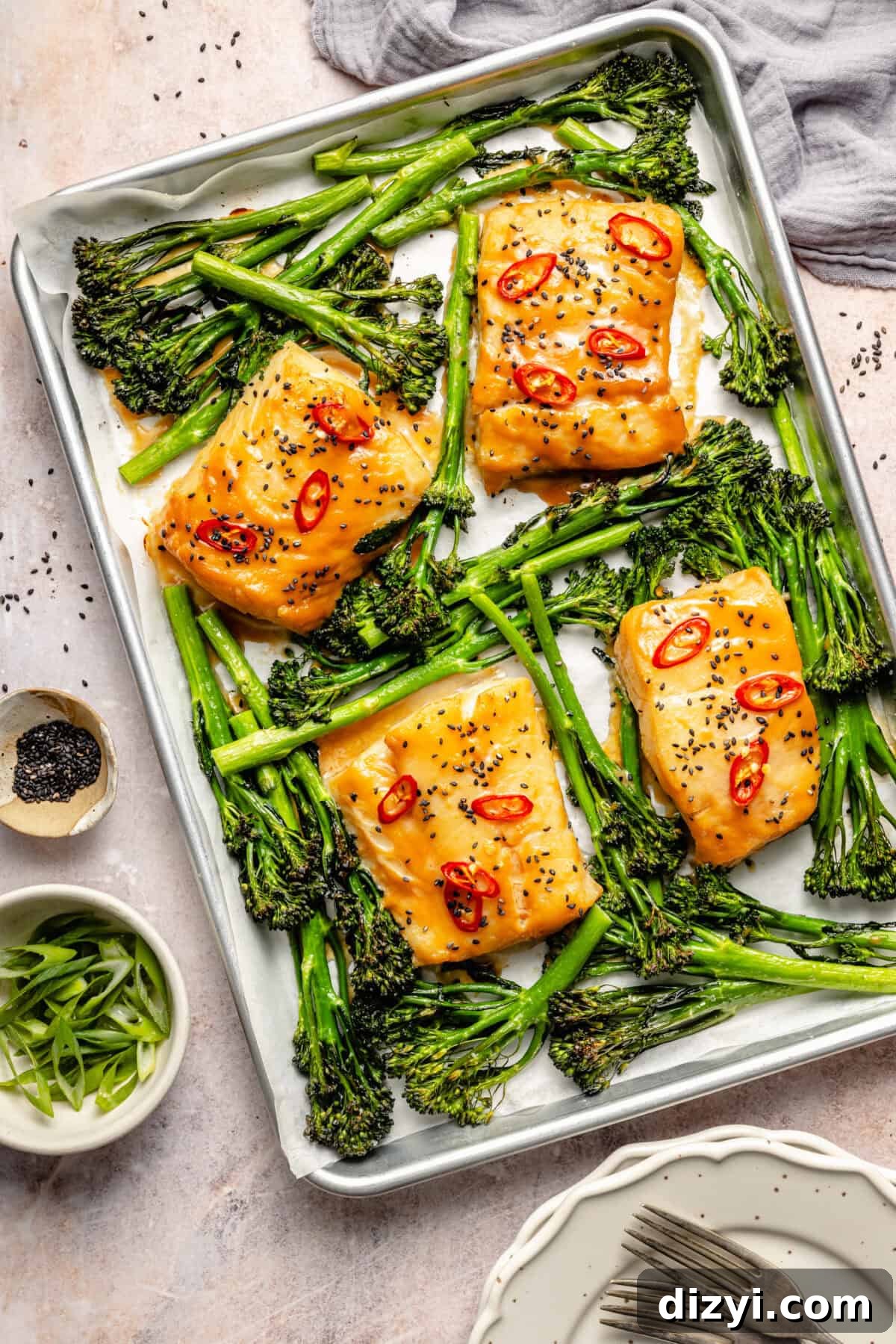 sheet-pan miso-marinated cod with broccolini and scallions on a light background