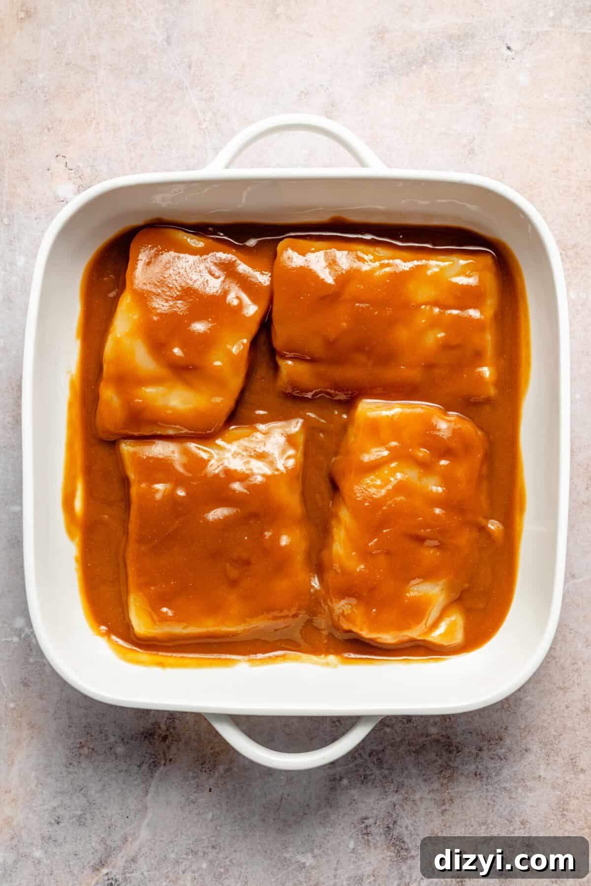 a white square baking dish with miso-marinated cod fillets on a light background