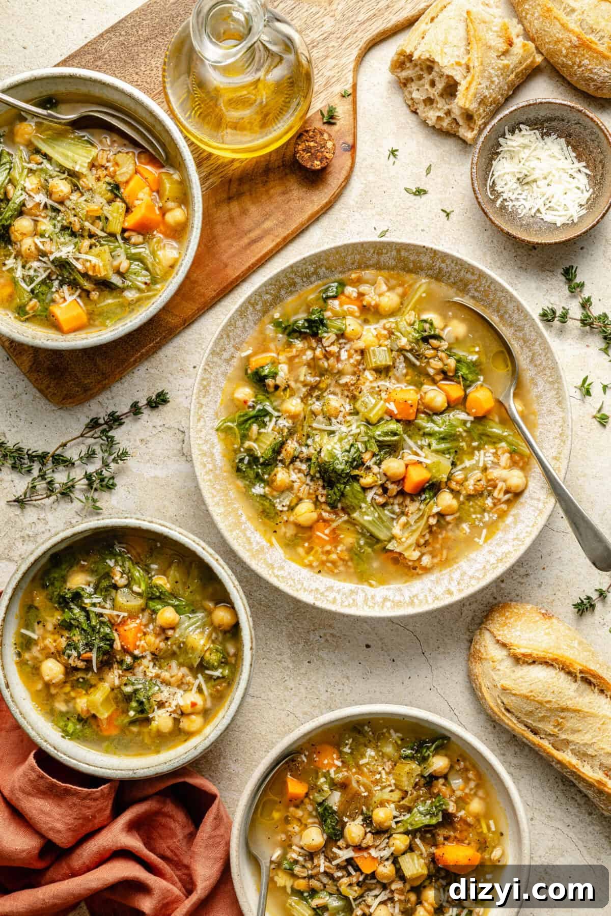 a few bowls of chickpea and farro soup with grated cheese, fresh herbs, and bread