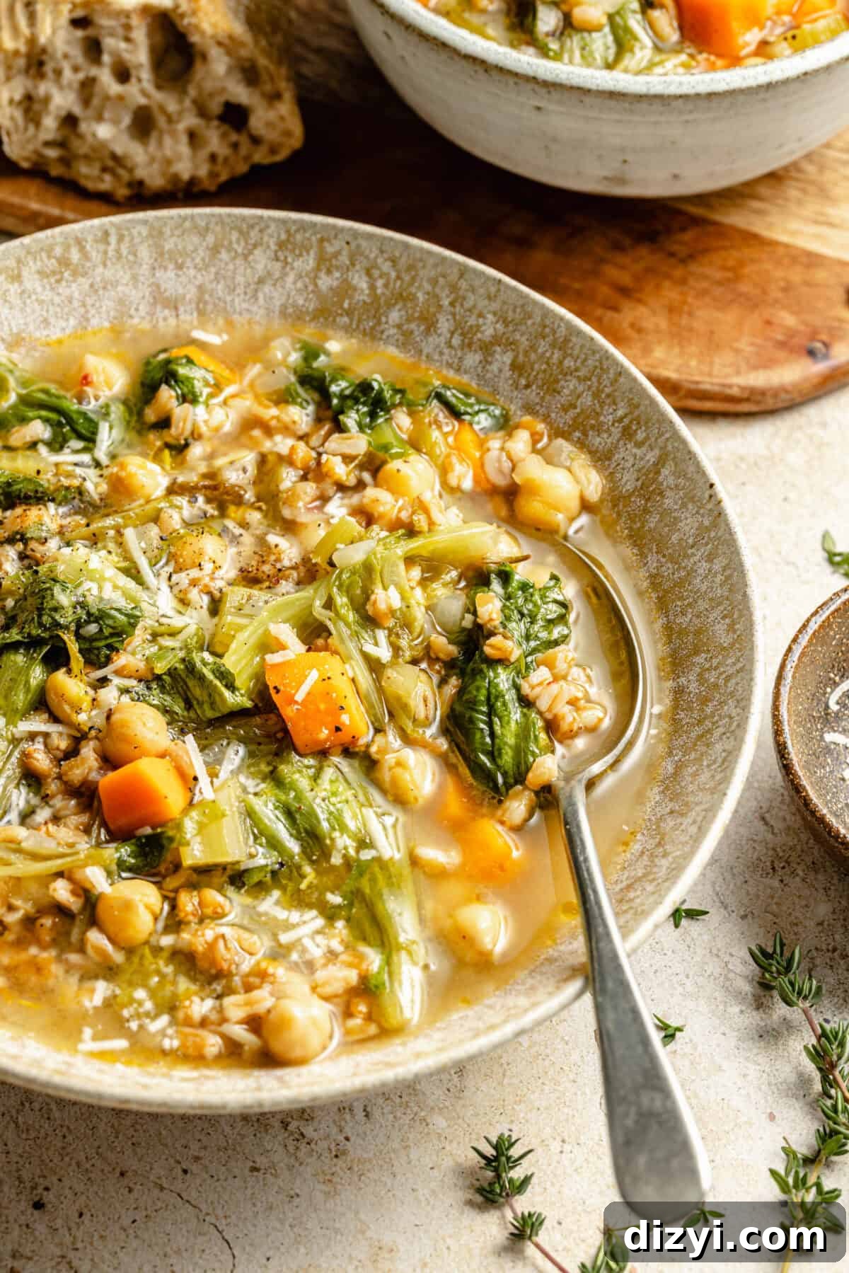 a large light tan bowl featuring chickpea and farro soup with fresh herbs