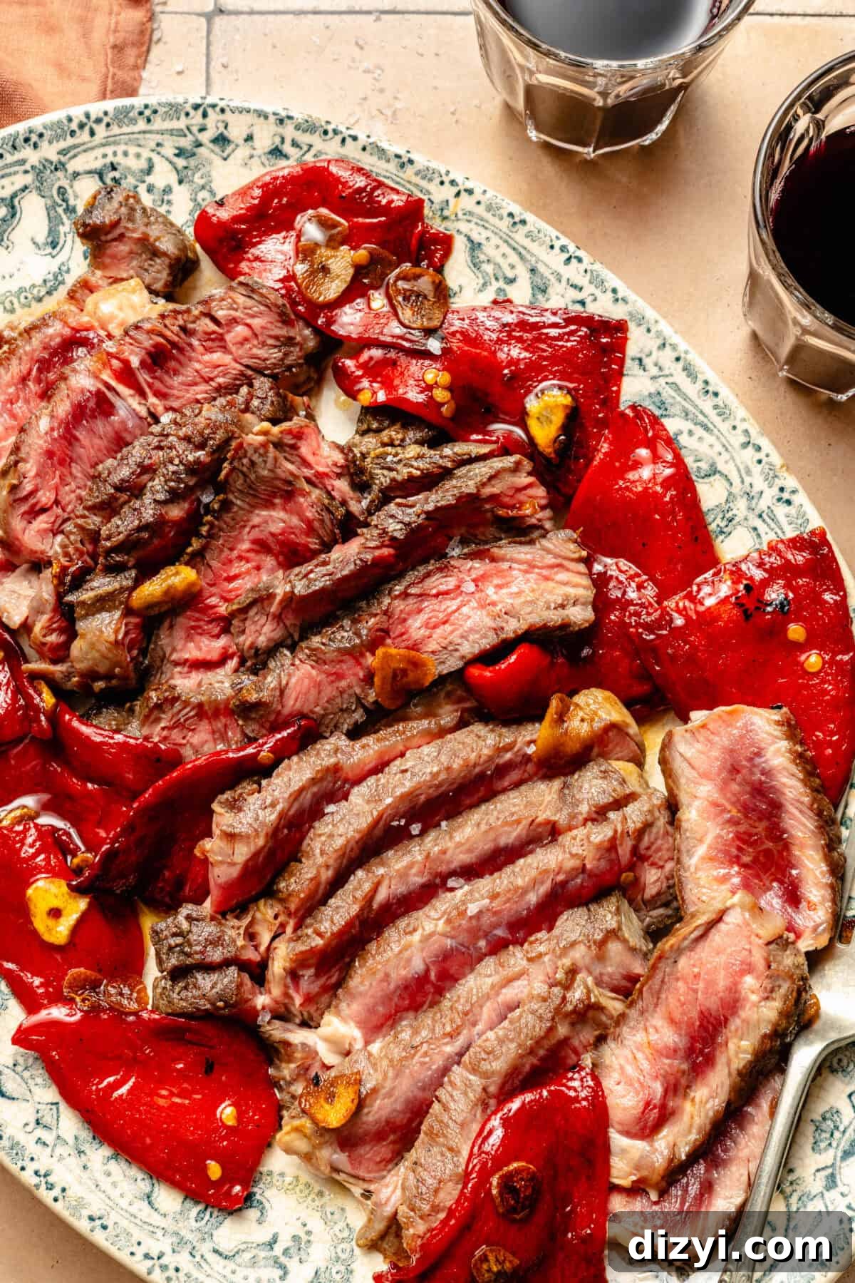 an up-close photo of seared rib eye steak with red peppers and garlic