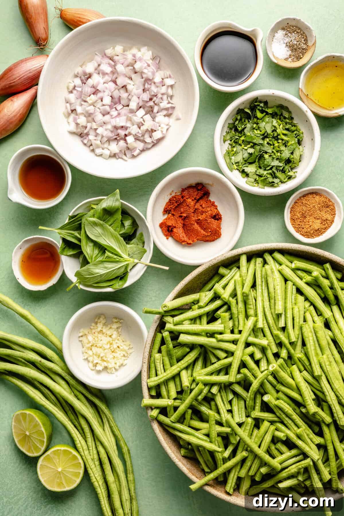 Prik King Stir-Fry: Thai Dry Red Curry 3 a flat-lay of ingredients for Pad Prik King including green beans, fresh herbs, and lime on a light green background