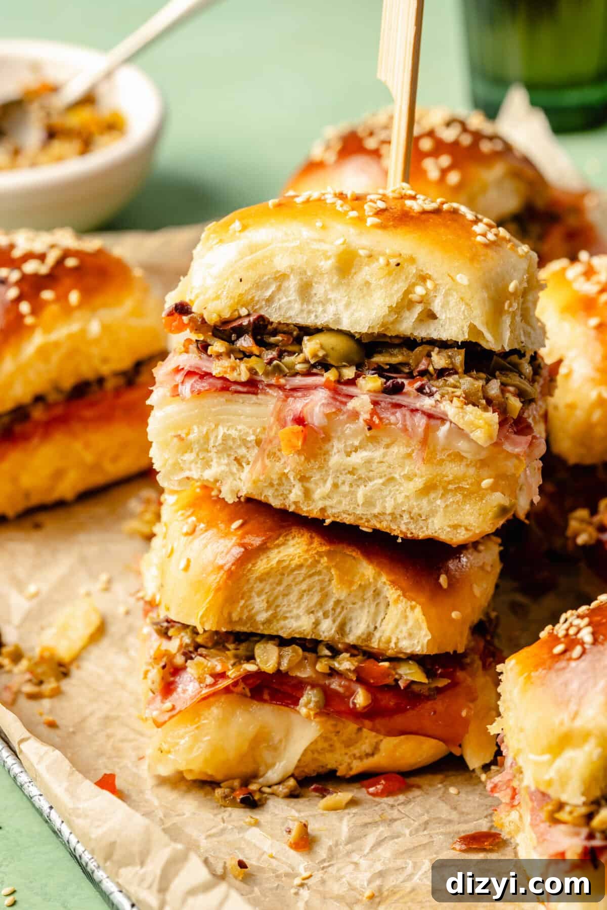 New Orleans Muffuletta Sliders with Olive Salad 5 a stack of muffuletta sliders with cured meat, provolone cheese, and olive salad